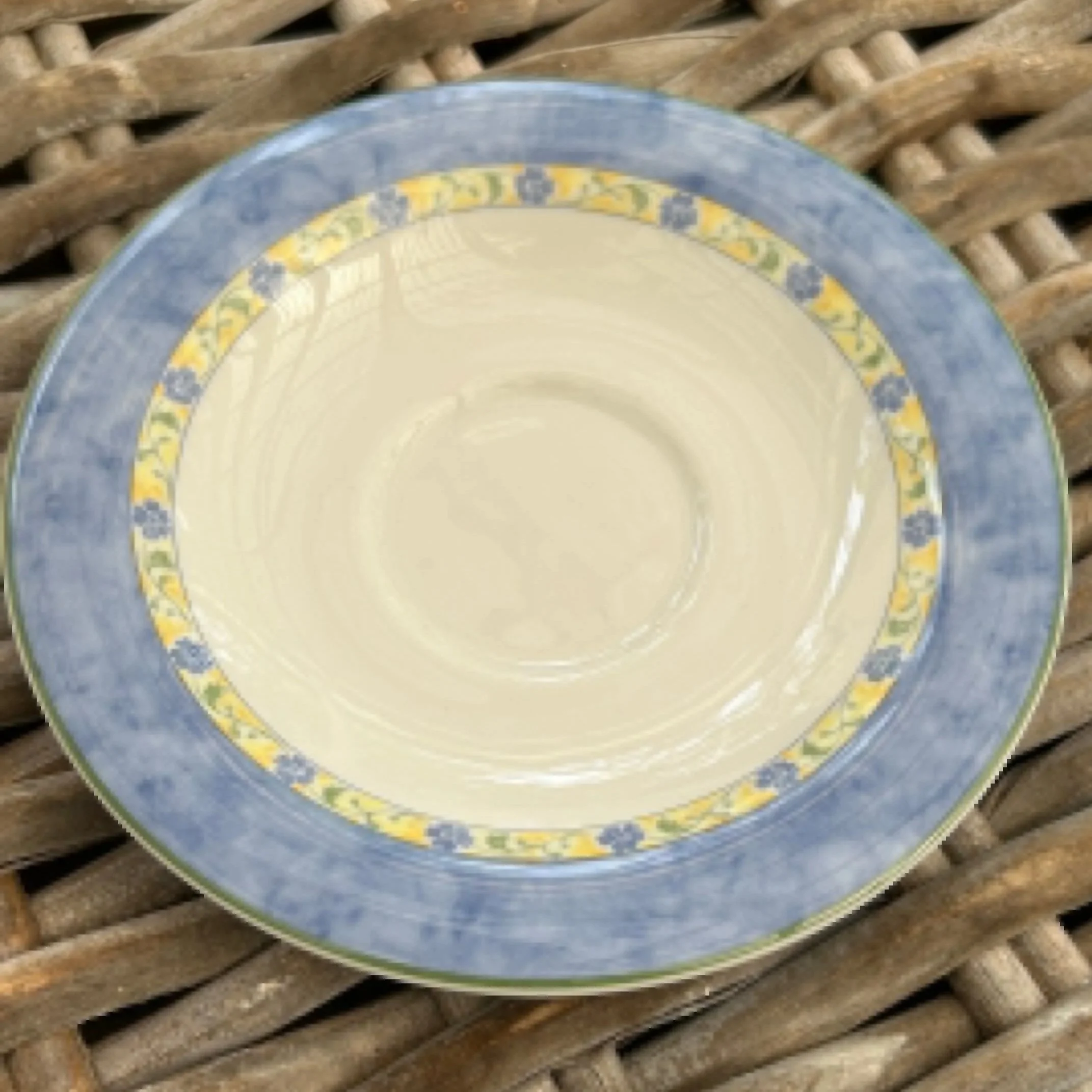 Flat lay of saucer on wicker surface with full floral pattern visible