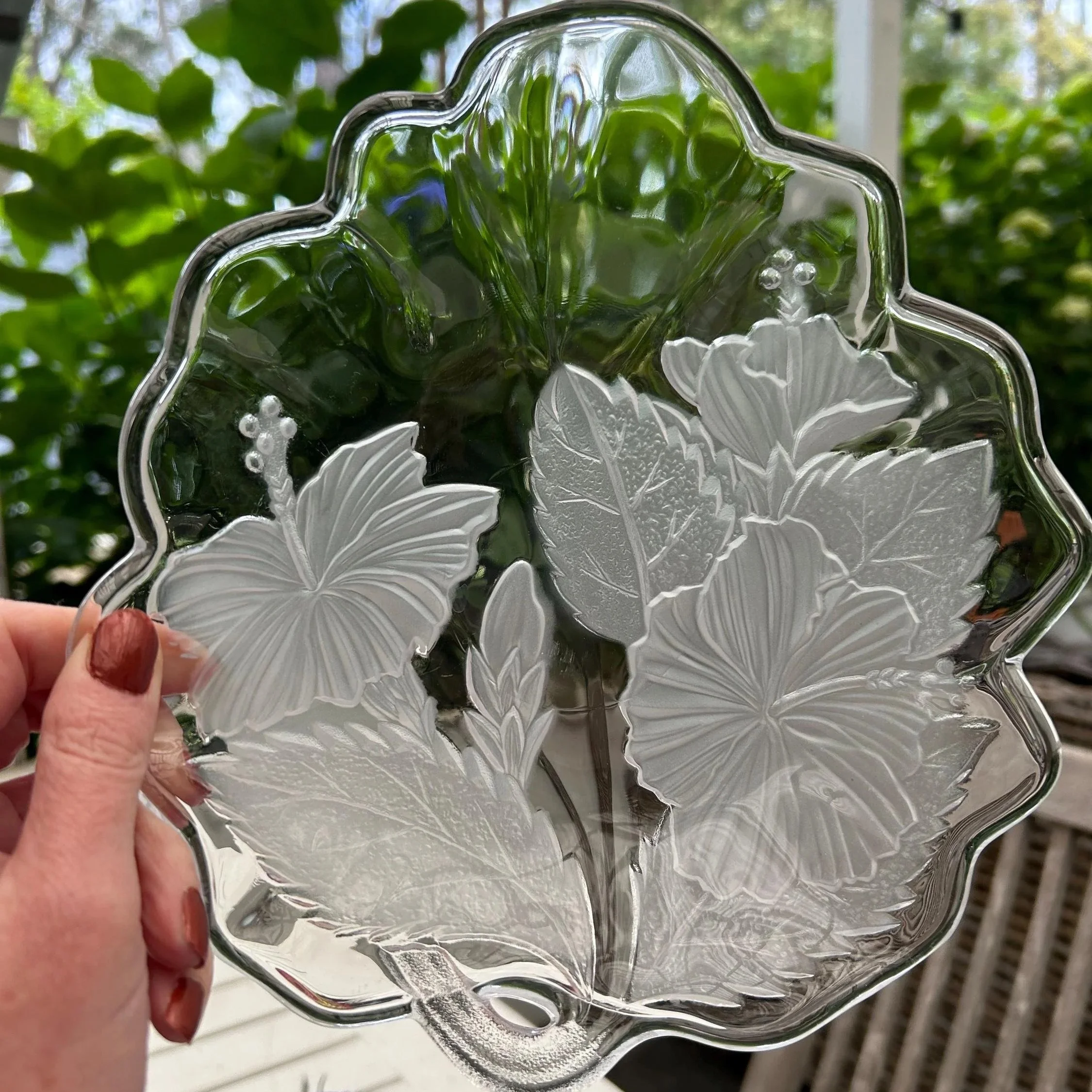 Bowl held up to light showing scalloped rim and floral relief.