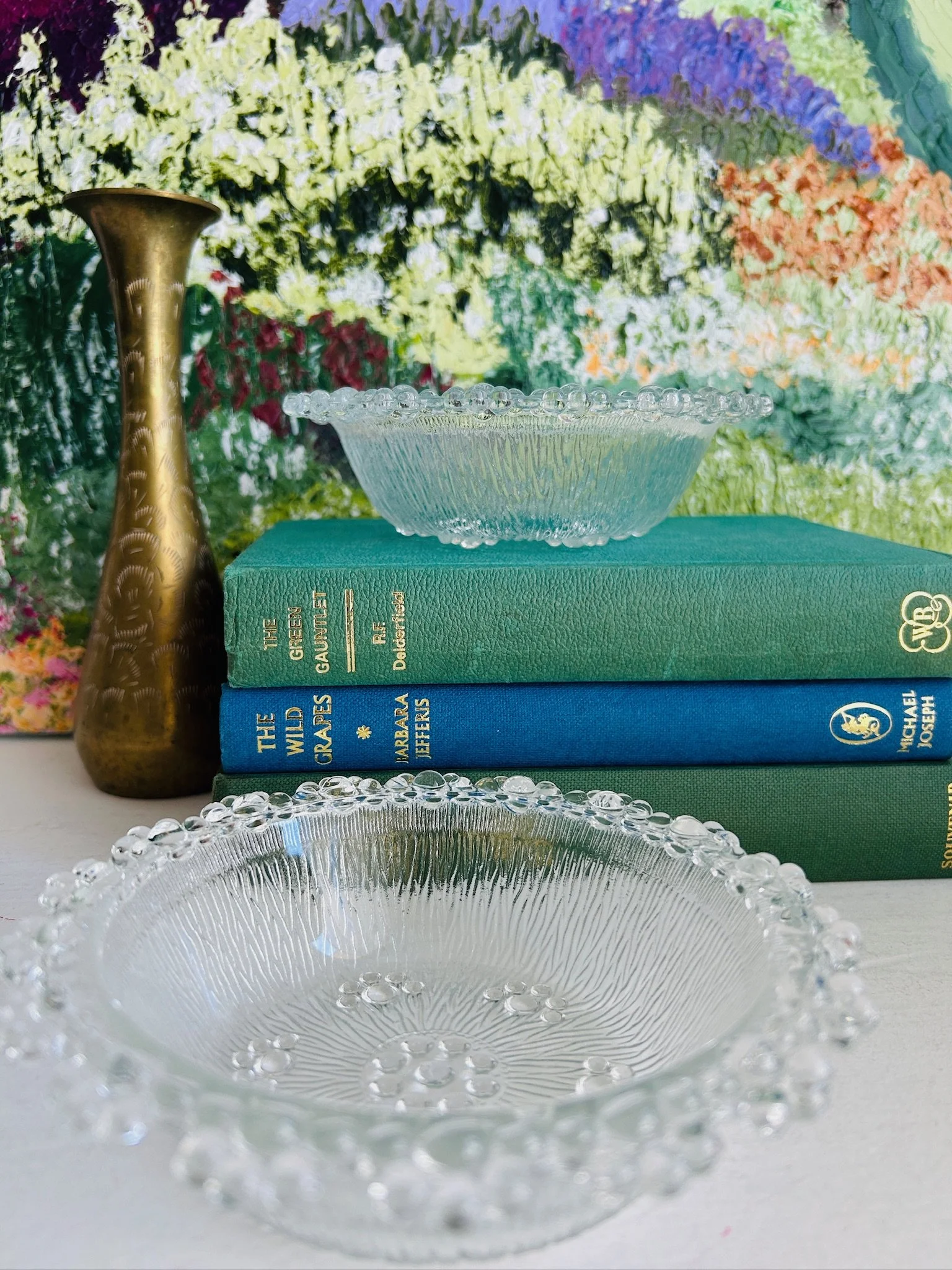 Styled display of the two Masserini Barocco bowls on stacked books beside a brass vase, showing scale and decorative use.