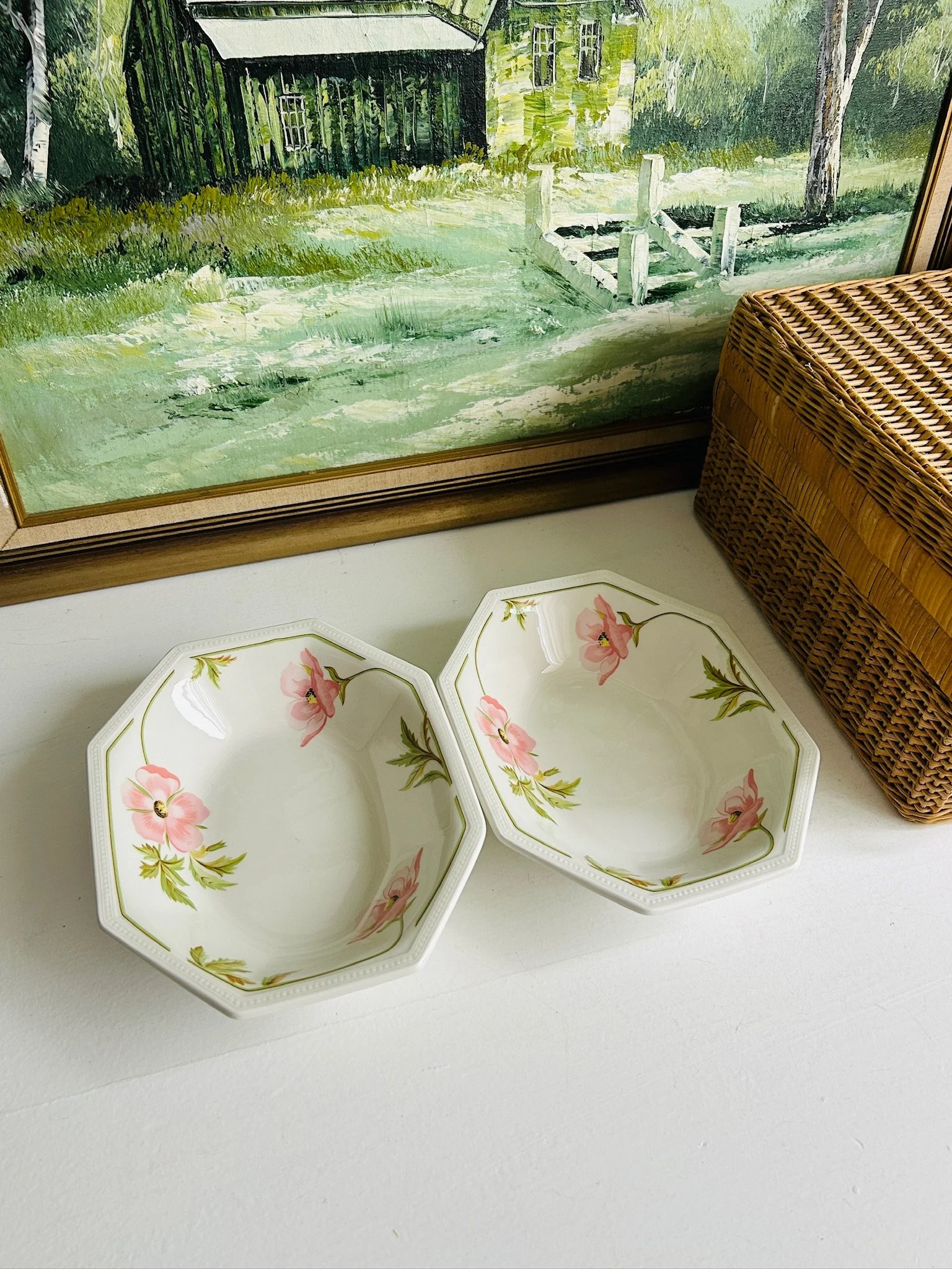 Close-up of the inside corner of one bowl, showing the pink flower, green foliage, and fine green line border.