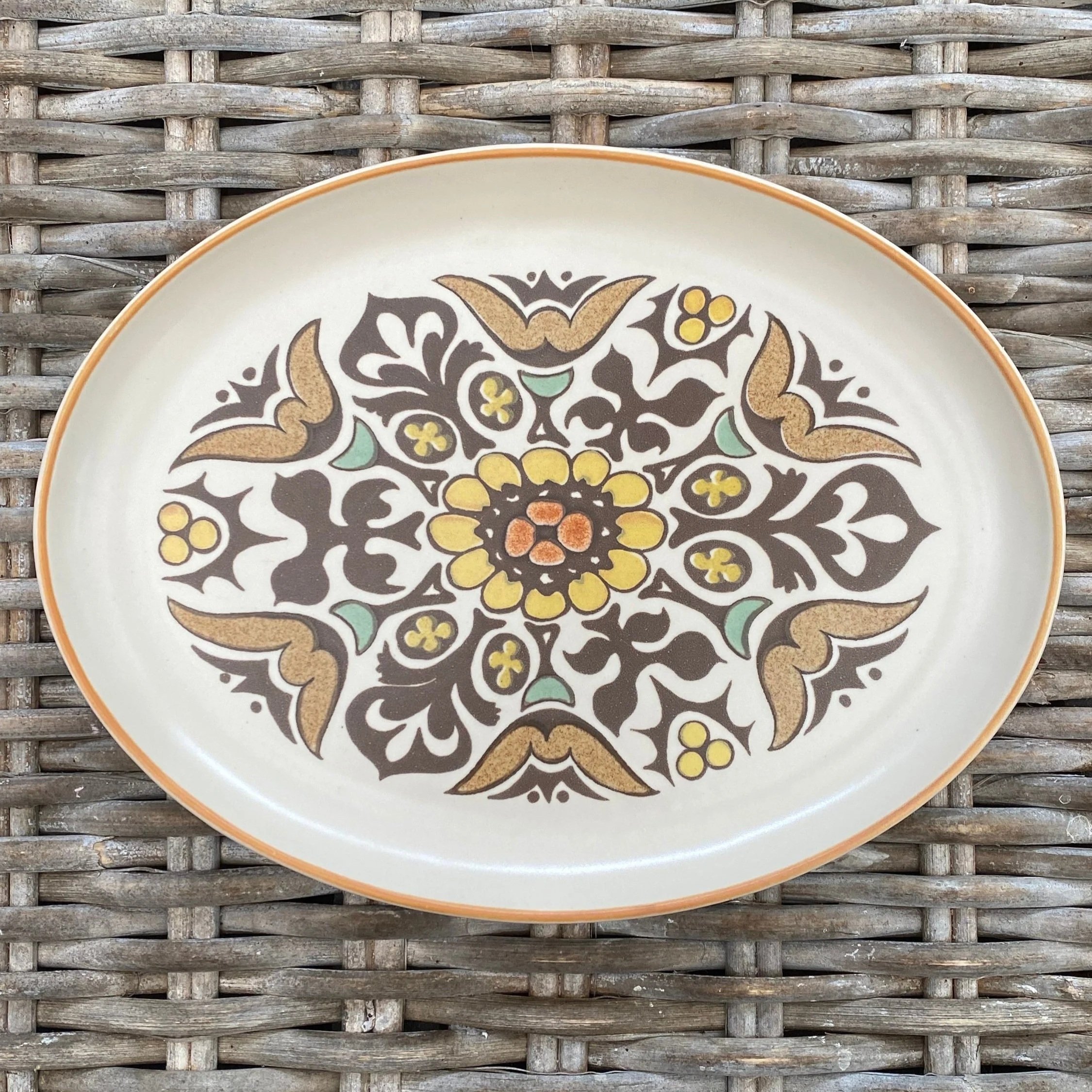 1: Full top view of Denby Langley Canterbury oval platter on wicker surface, showing full floral pattern