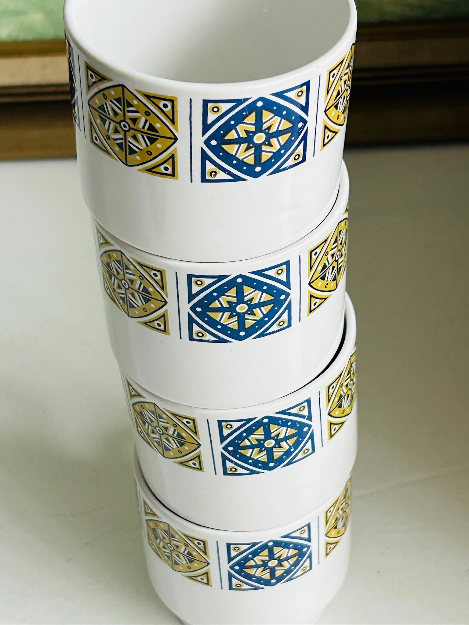 Close-up of stacked Staffordshire Midas cups showing the repeating geometric border and pedestal-style bases.