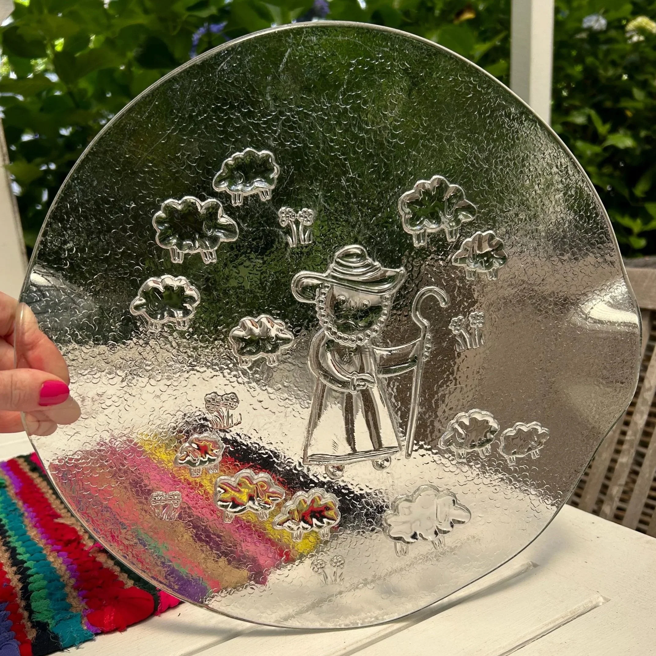 Hand holding a round IVV Italian glass platter with shepherd and sheep scene