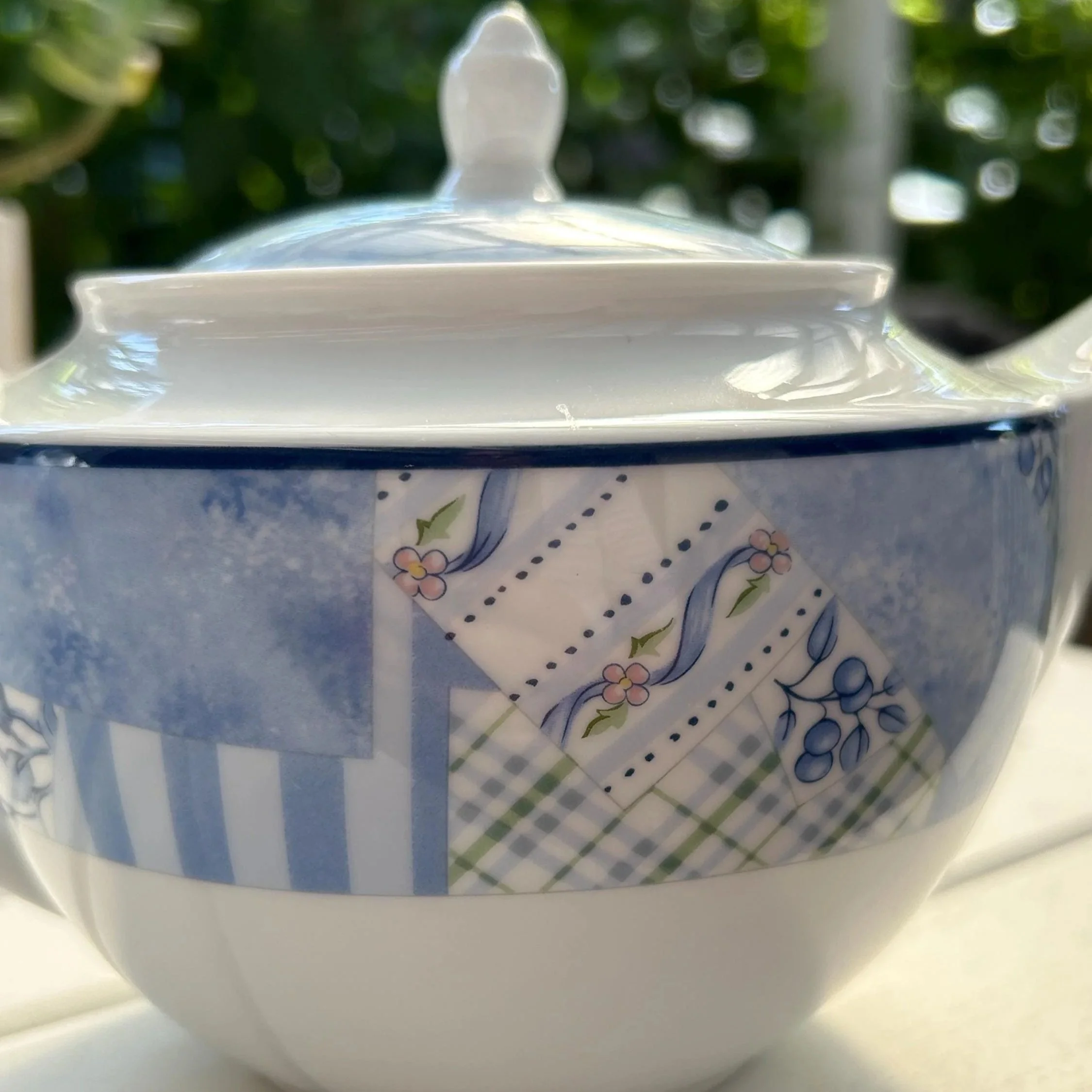 Close-up of the lidded sugar bowl showing the patchwork pattern and finial lid detail