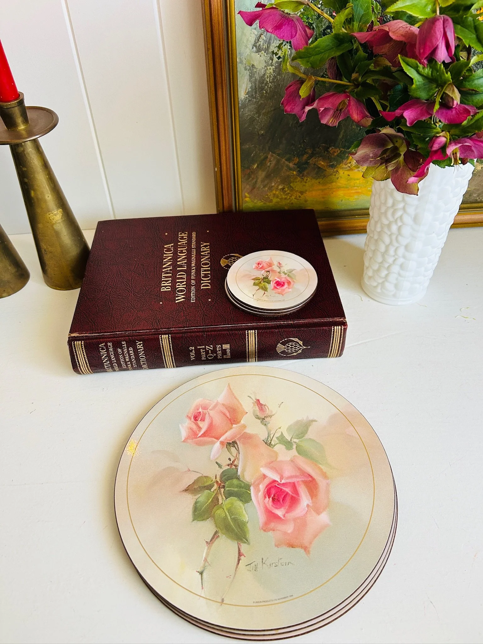 Pink rose Jason placemat and matching coaster styled with brass candlesticks, milk glass vase and a gilt framed floral painting