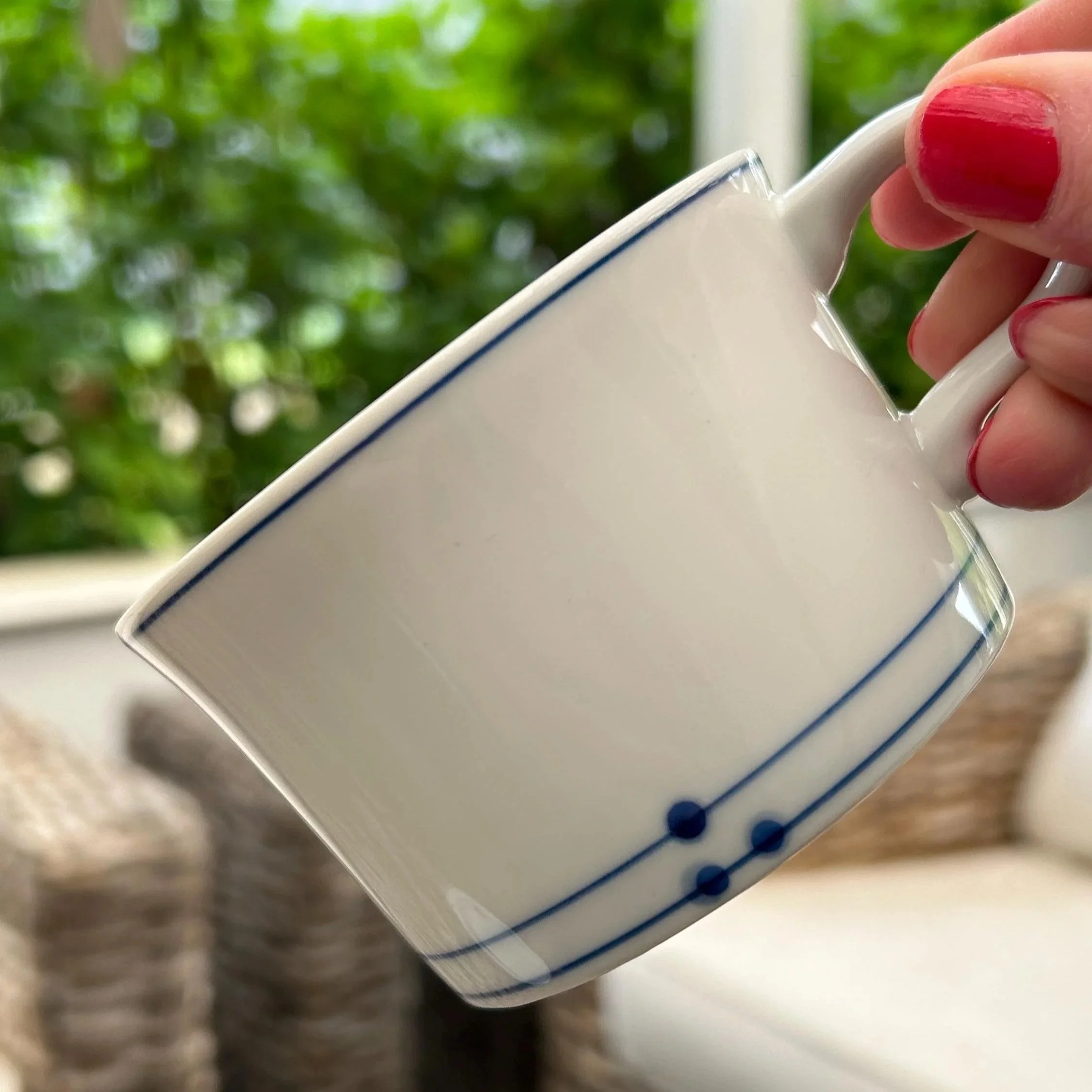 Cup held in hand – off-white body with minimalist blue trim