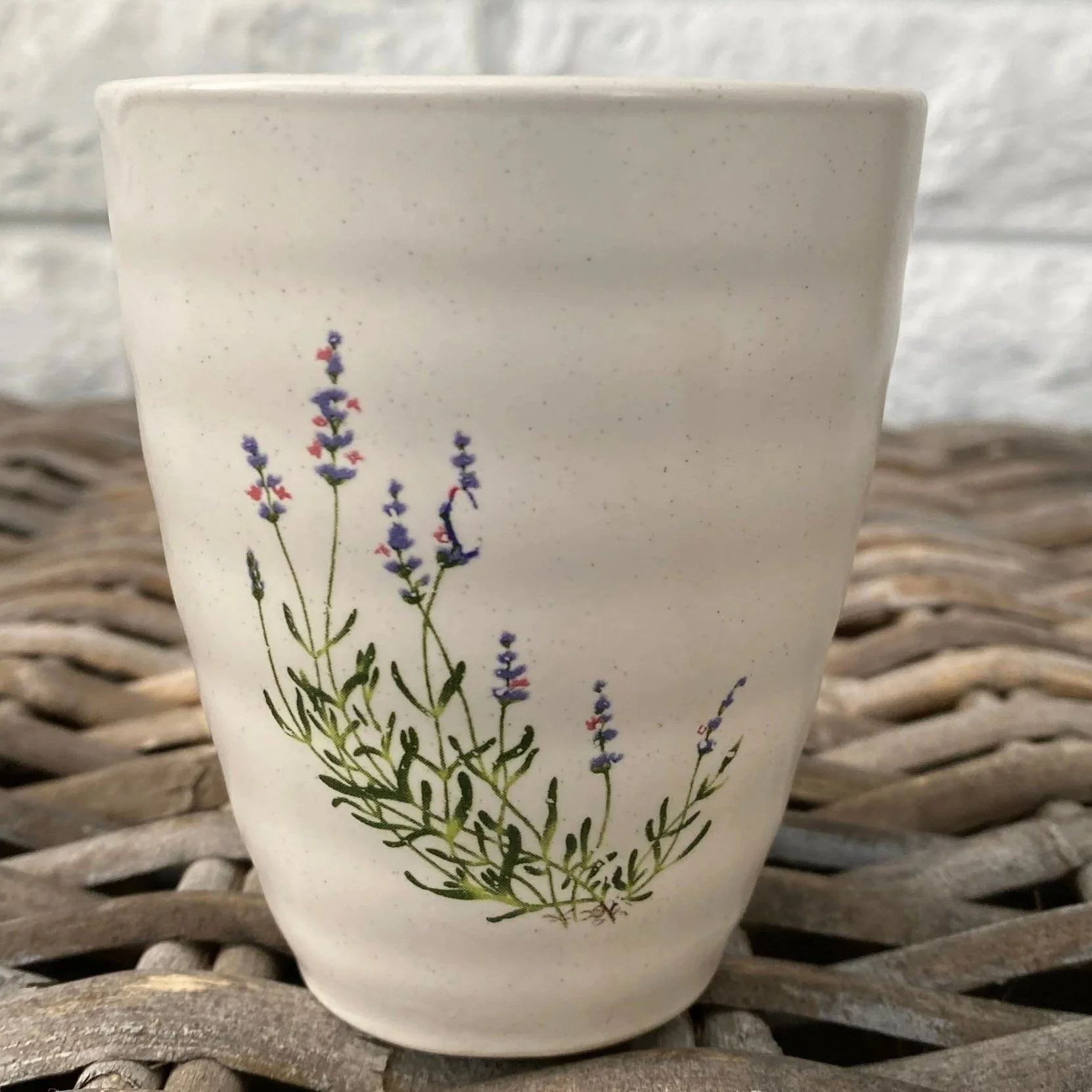 Close-up of the ceramic cup showing the hand-painted lavender sprig design and softly textured glaze
