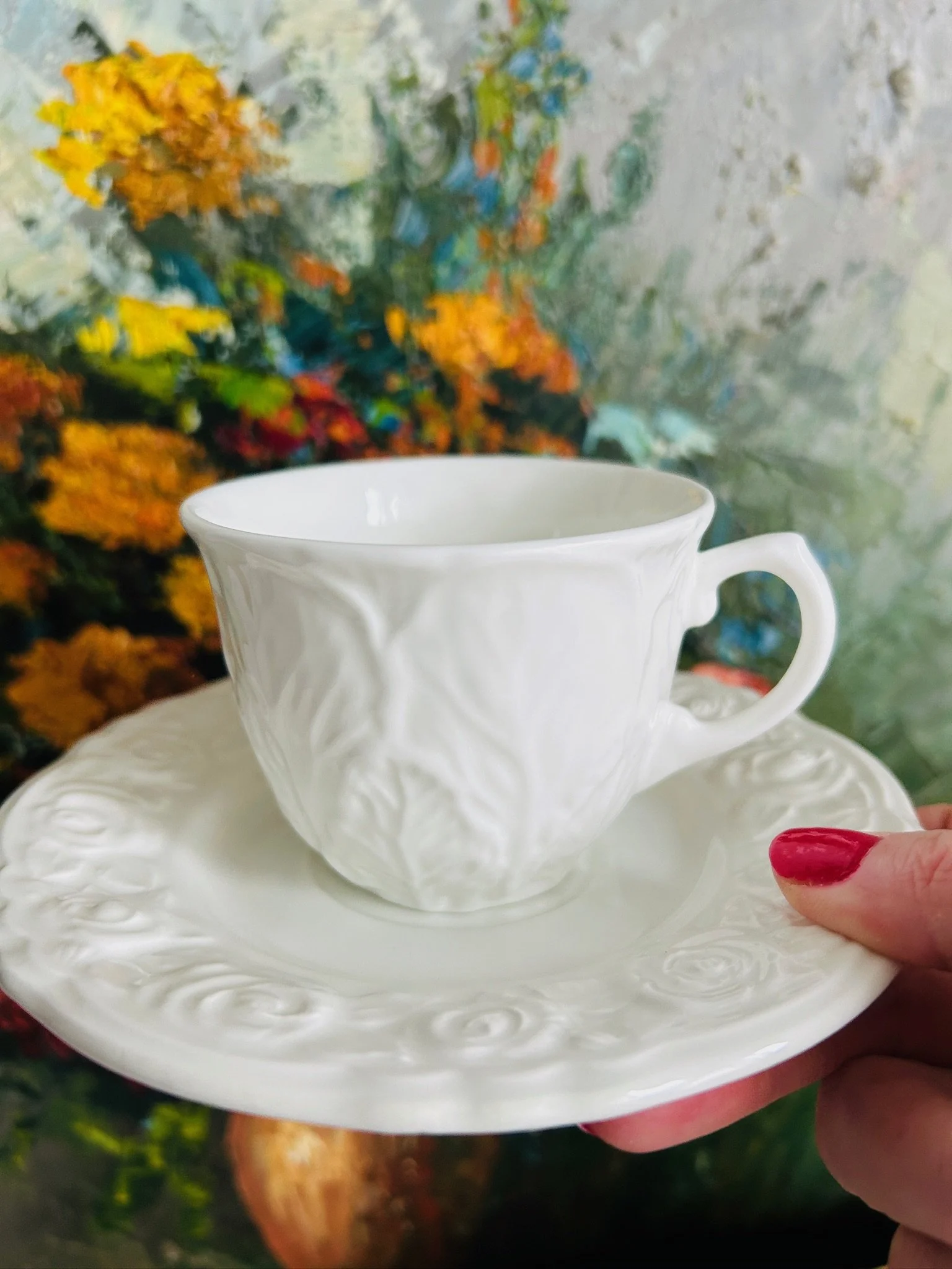 Front view of the cup and saucer together, showing the full mixed set with embossed floral and botanical details.