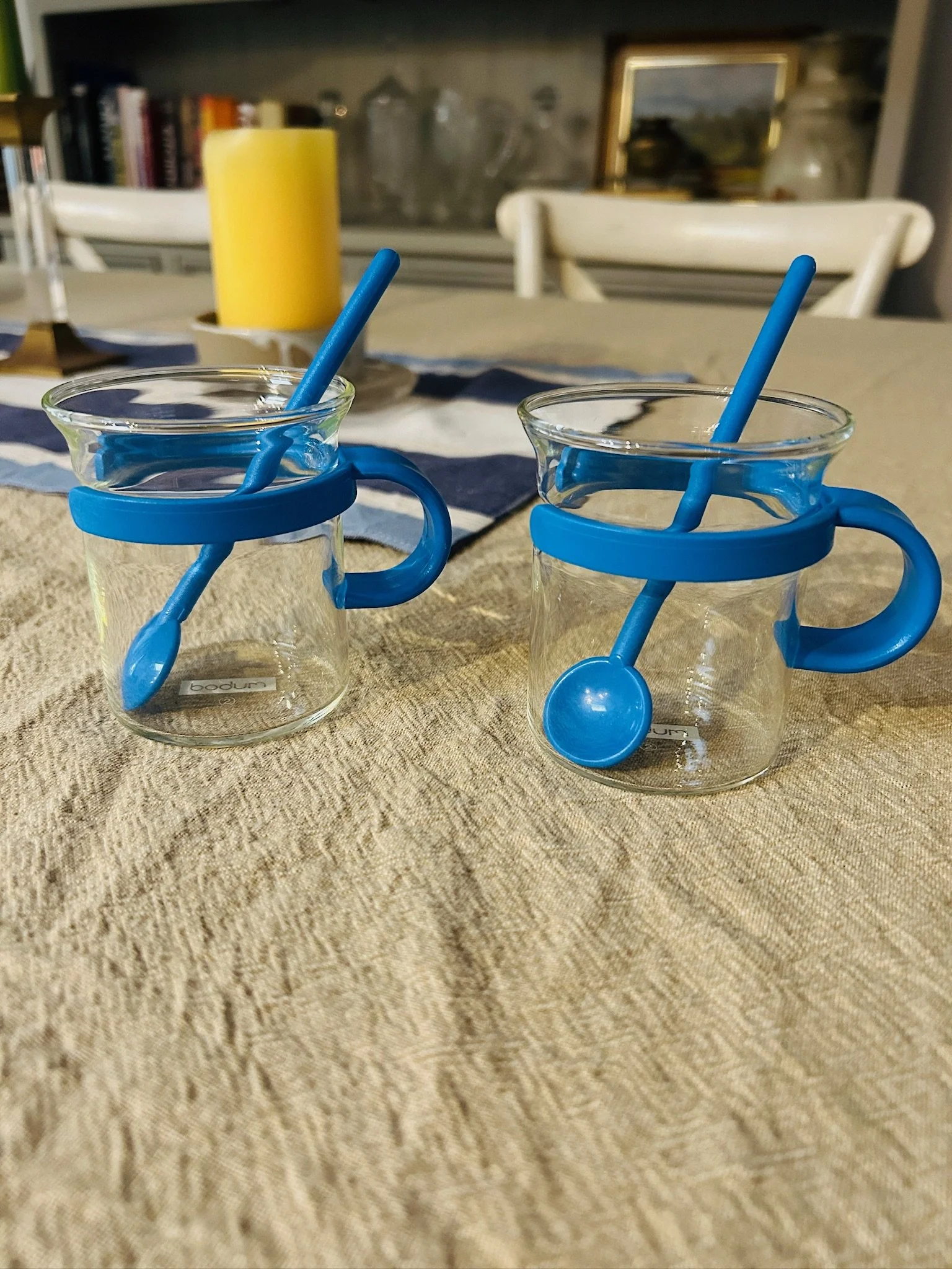 Pair of blue Bodum Picard cups styled on a cloth-covered table, each with a matching blue spoon resting inside.