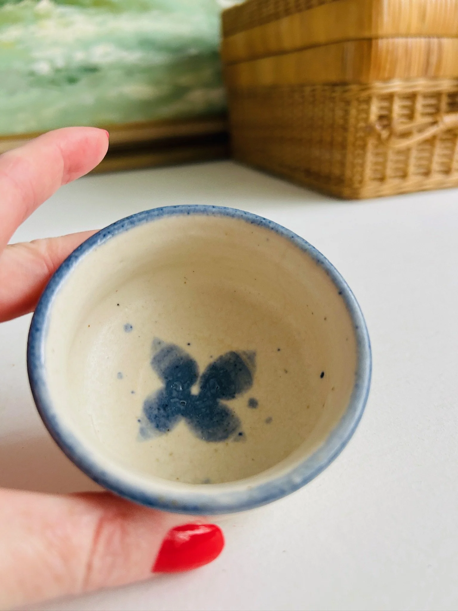 Top-down view of the ceramic bowl held in hand, highlighting the blue floral centre and rounded blue rim