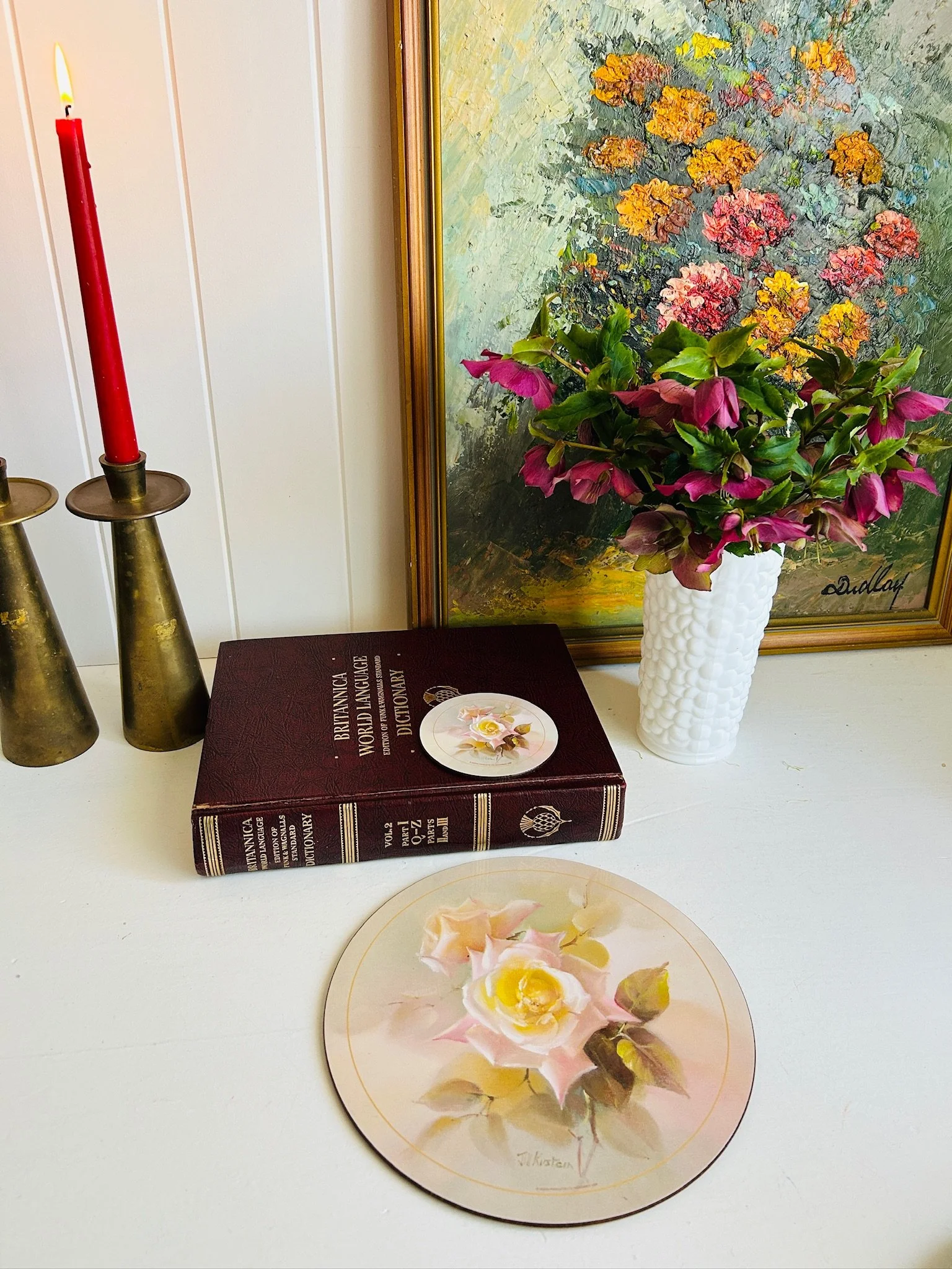 Yellow rose Jason placemat styled with brass candlesticks, red taper candle and a matching coaster on a vintage dictionary