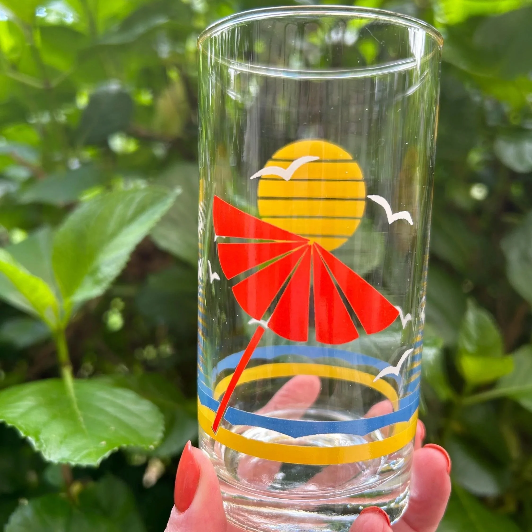 Close-up of one tumbler showing red umbrella and yellow sun motif