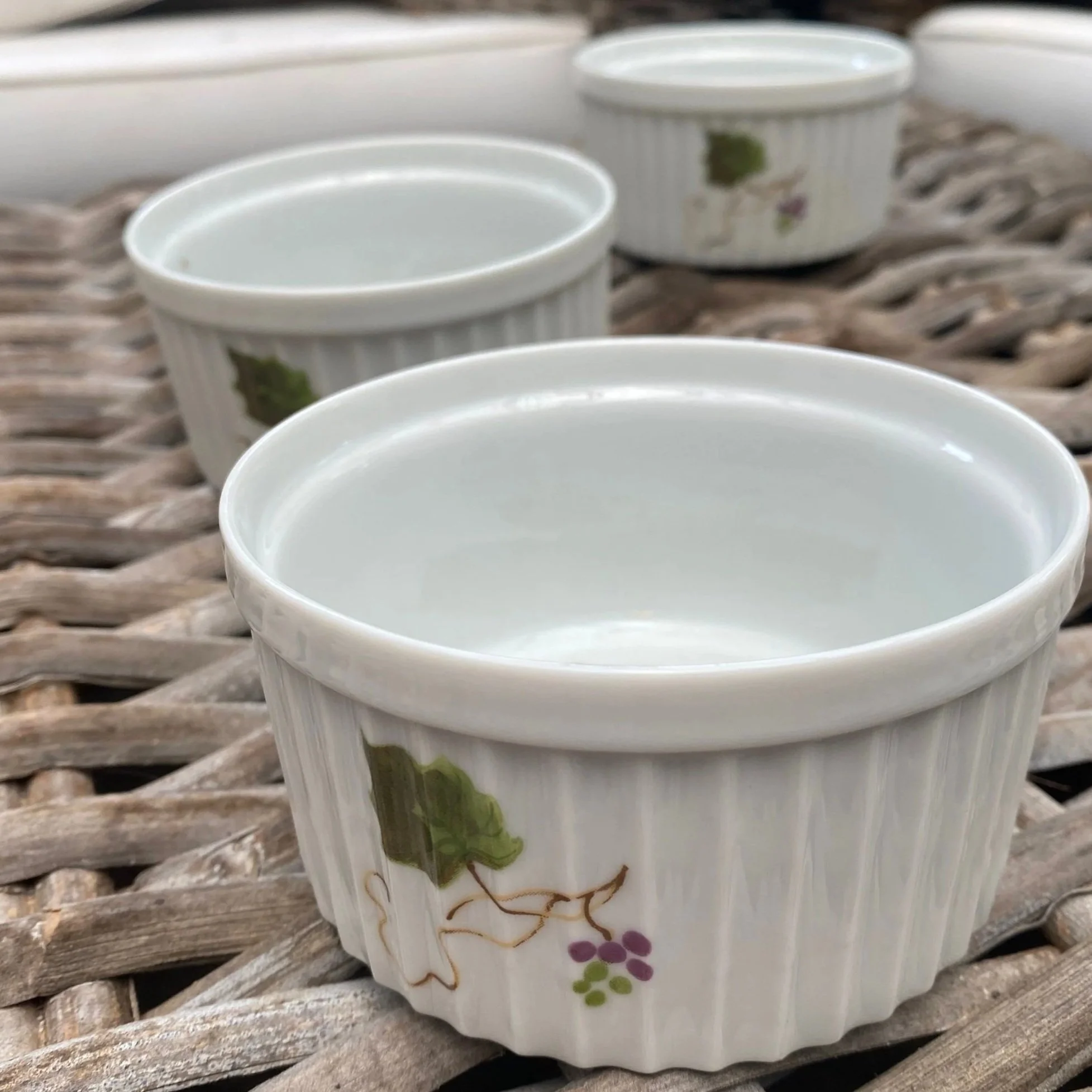 Three vintage Japanese stoneware ramekins with grapevine design on woven surface