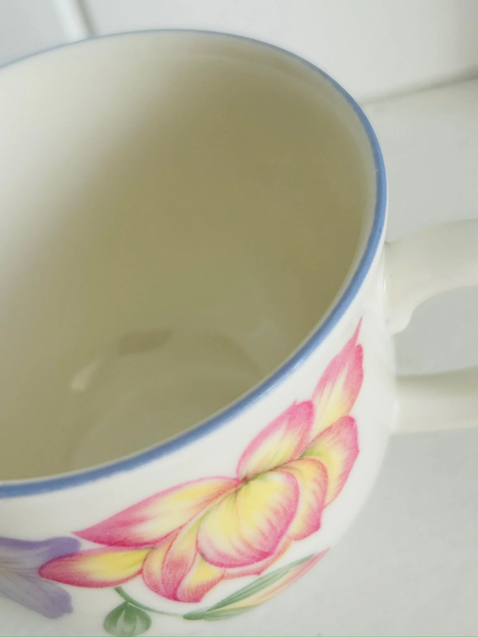 Close-up of the teacup interior and rim, showing the pale cream glaze and a small interior mark