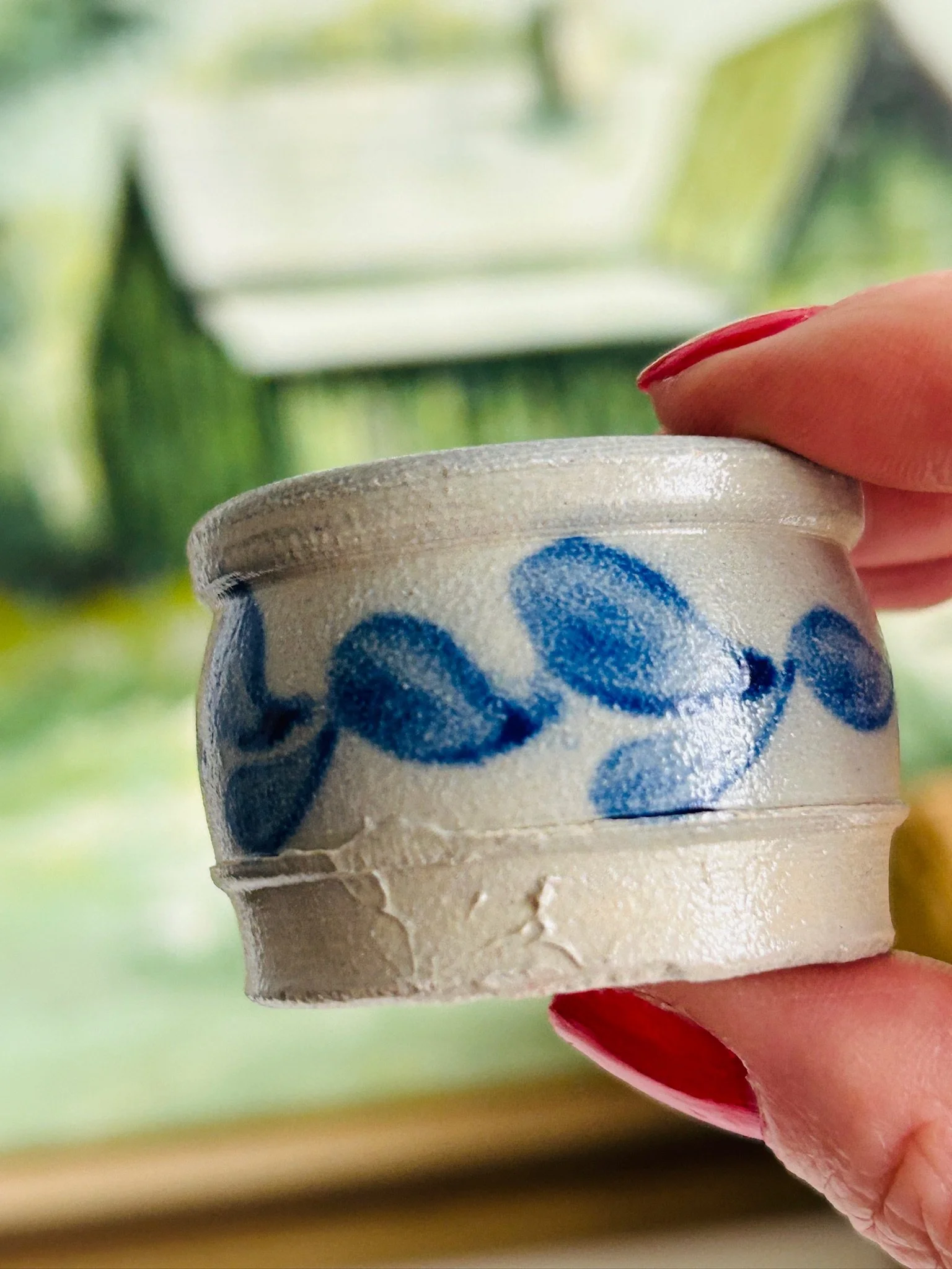 Close side view of the salt cellar held in hand, highlighting the cobalt blue leaf detail and rolled rim