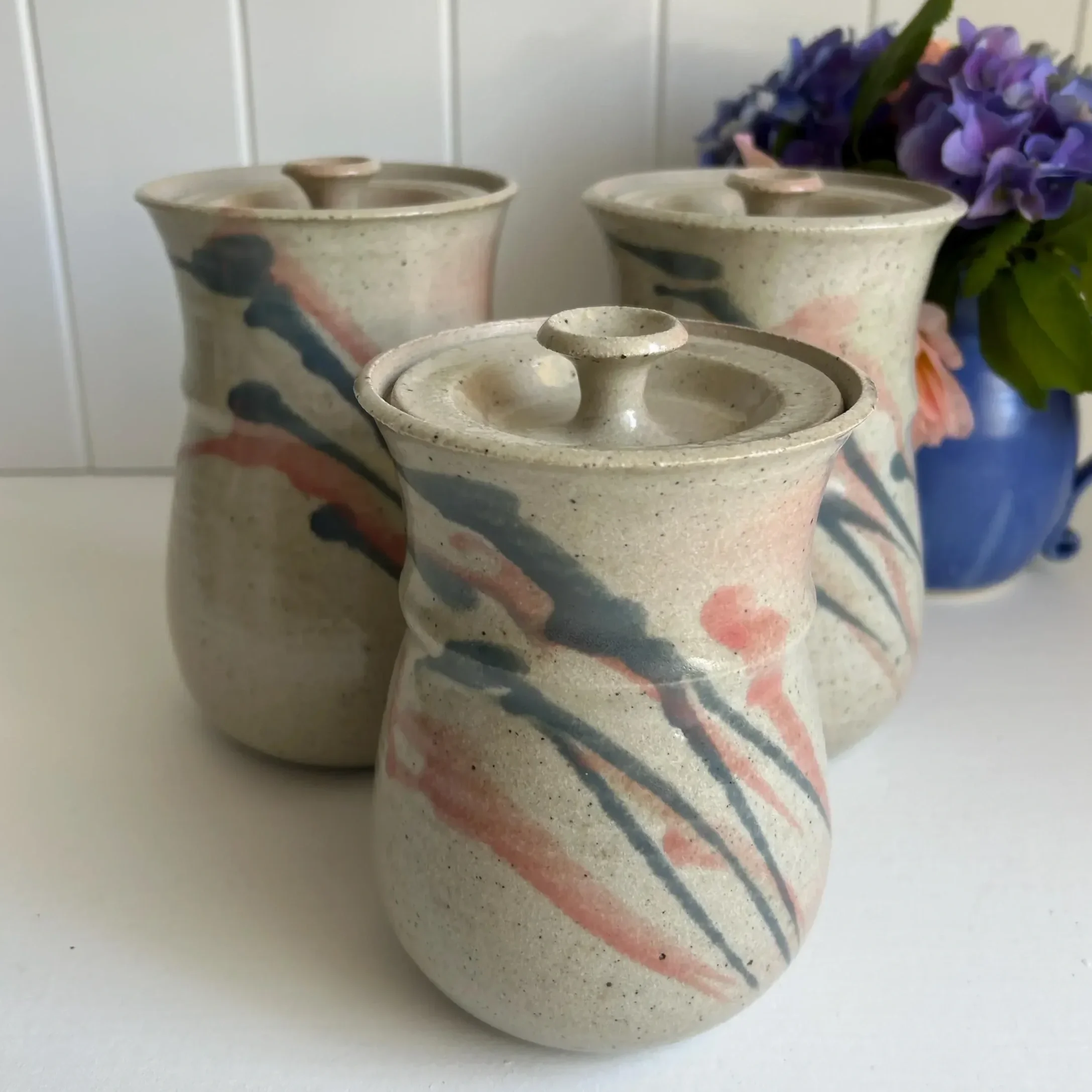 Front view of 3 Norwood Pottery canisters with lids, brushstroke design visible