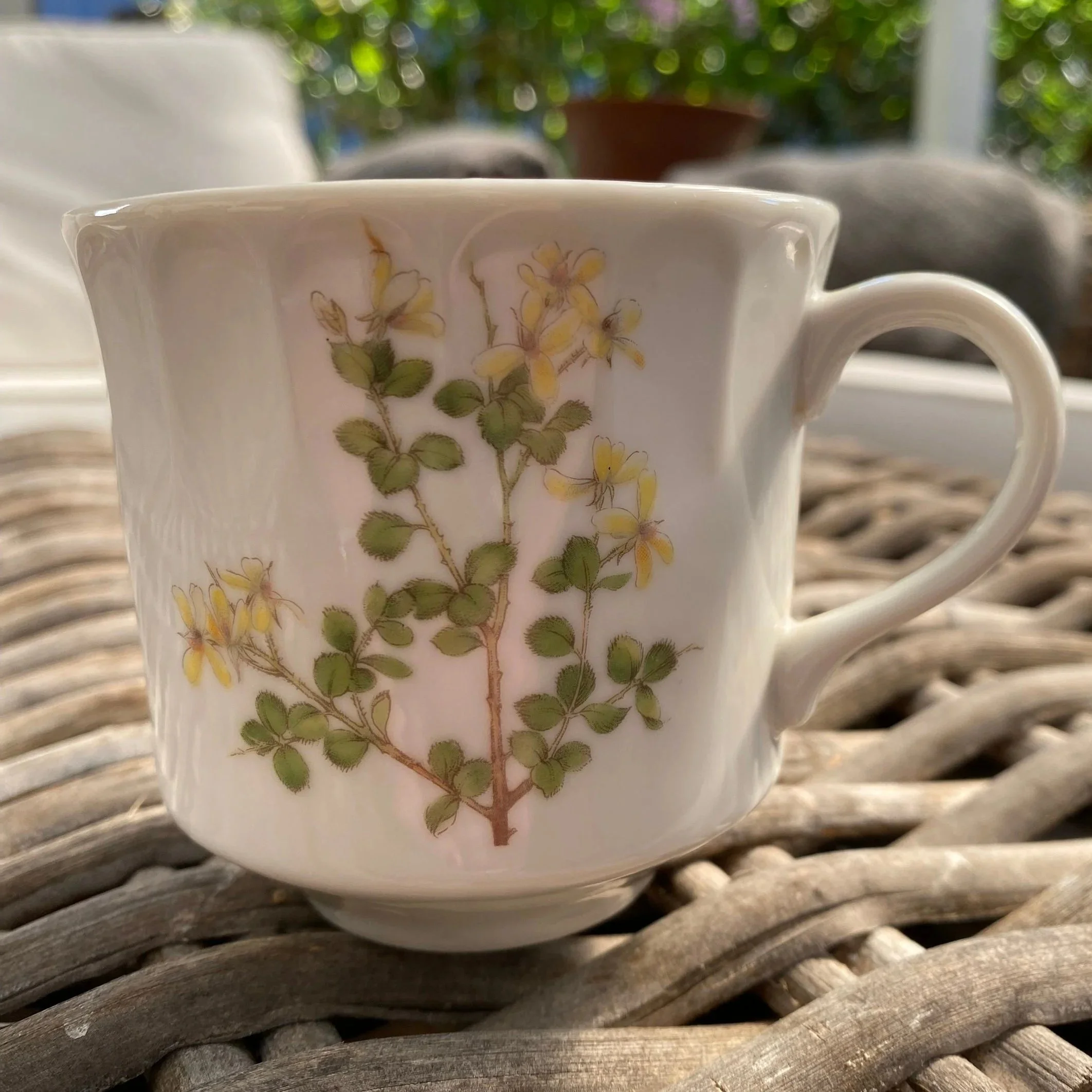 Front view of vintage white ribbed ceramic cup with yellow and green floral pattern