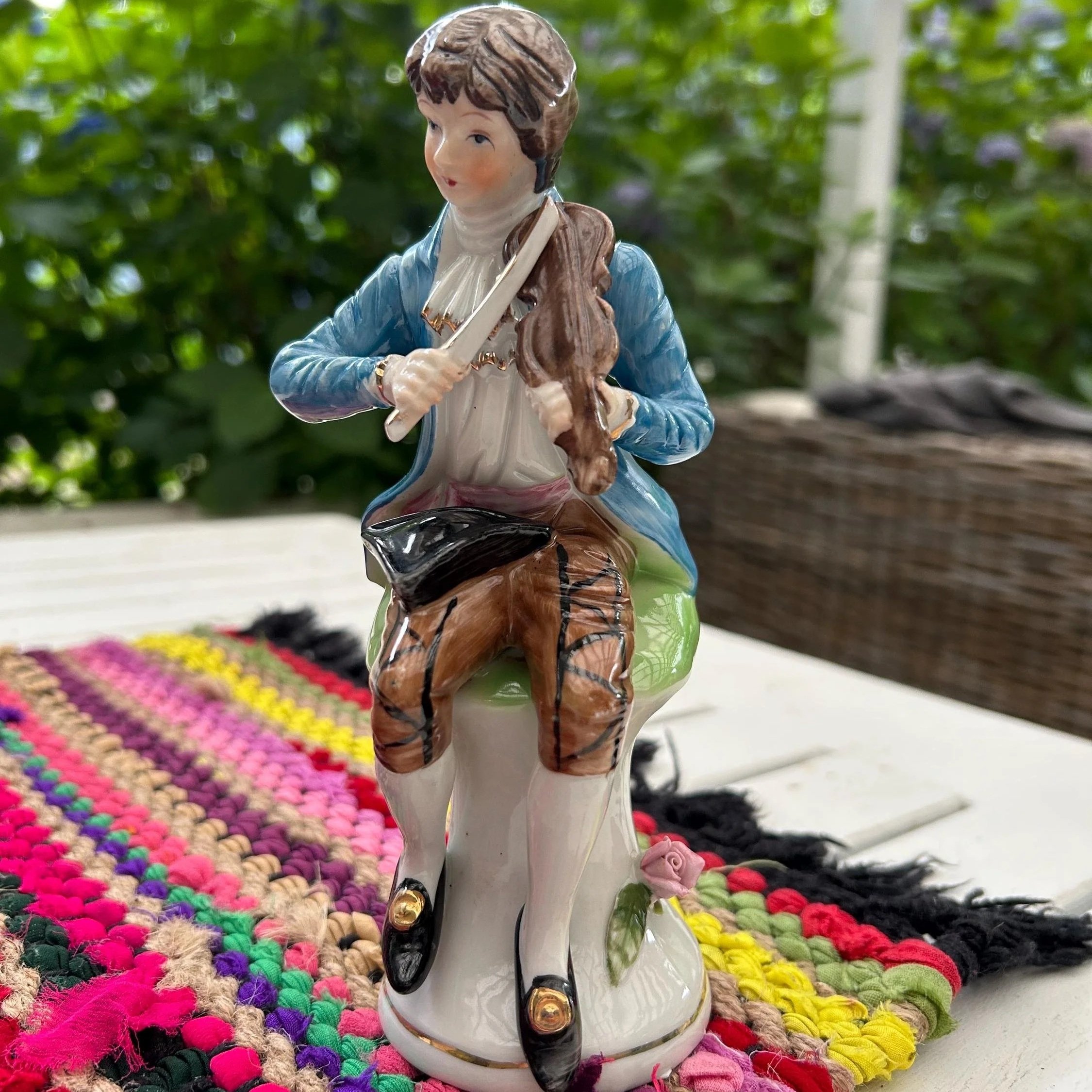 Front view of porcelain violinist figurine seated on white and green base