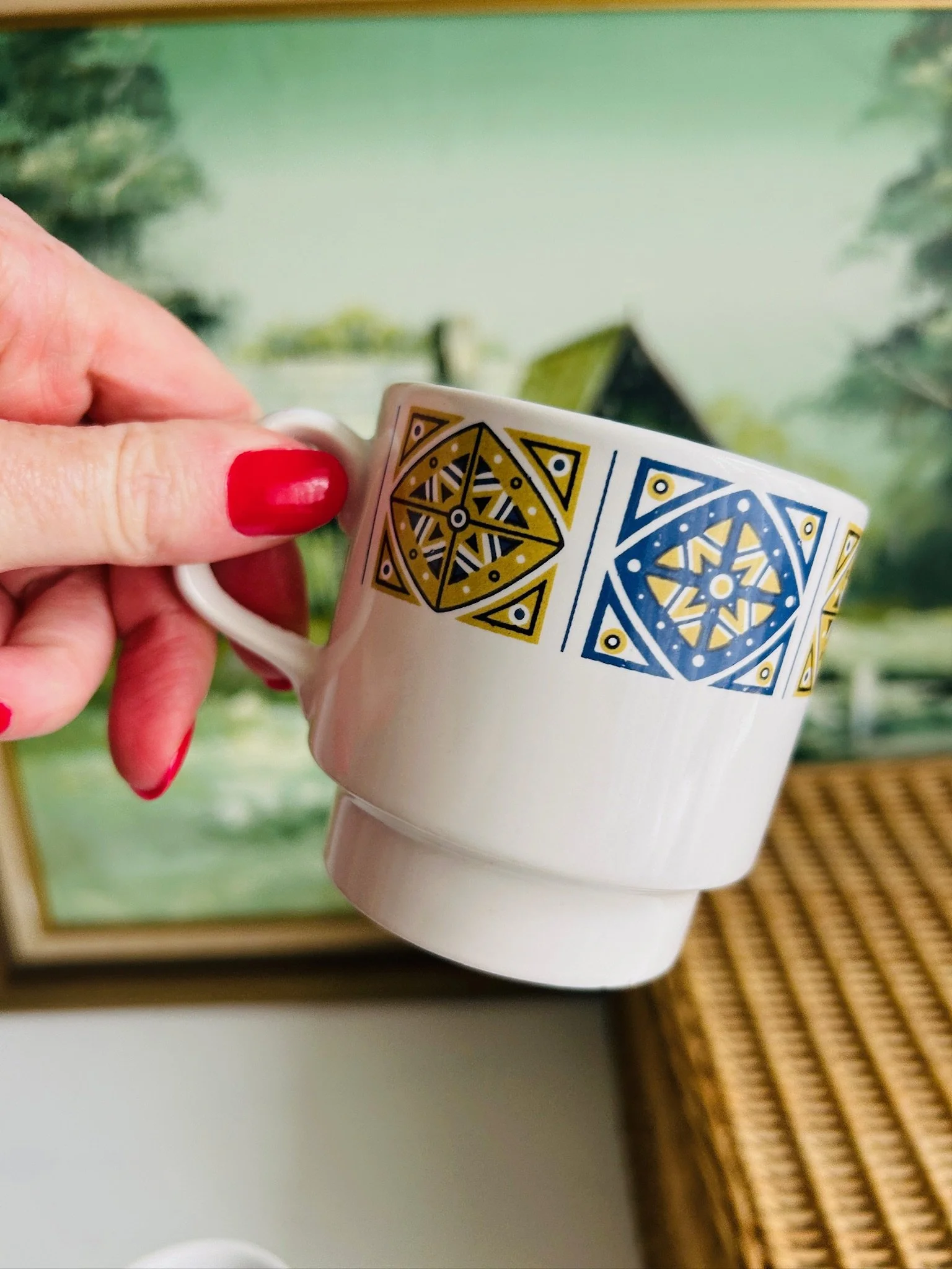 Staffordshire Midas cup held at an angle with handle visible and geometric pattern wrapping around the rim.