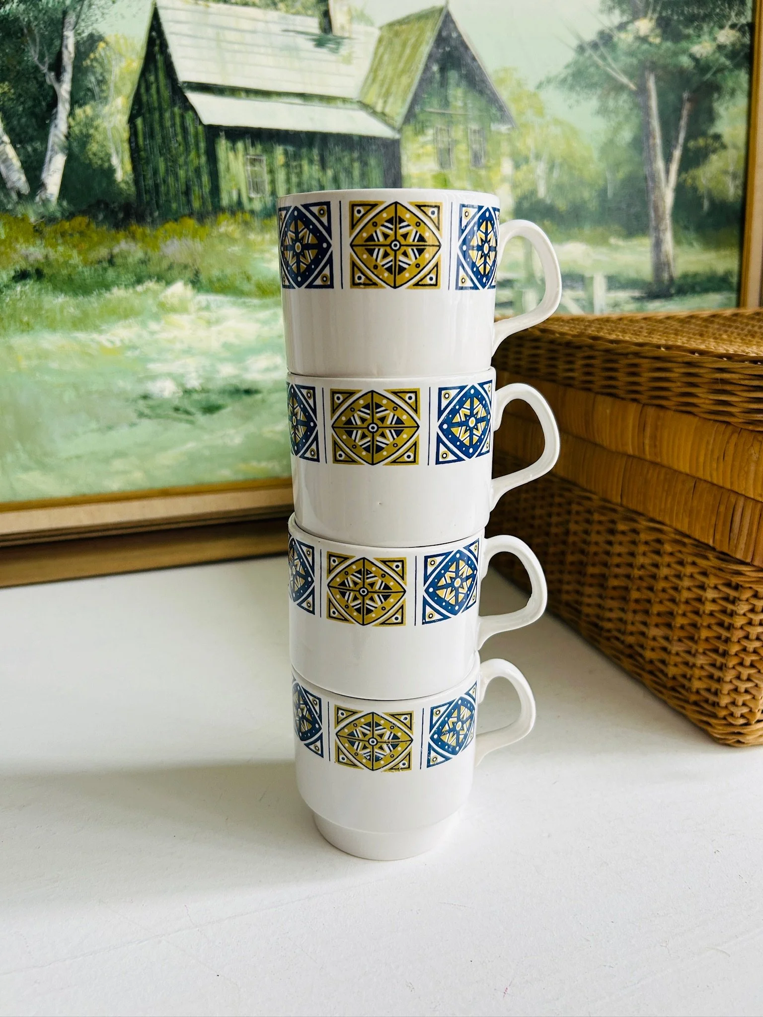 Side view of four Staffordshire Midas stackable cups arranged in a tall stack beside a wicker box.