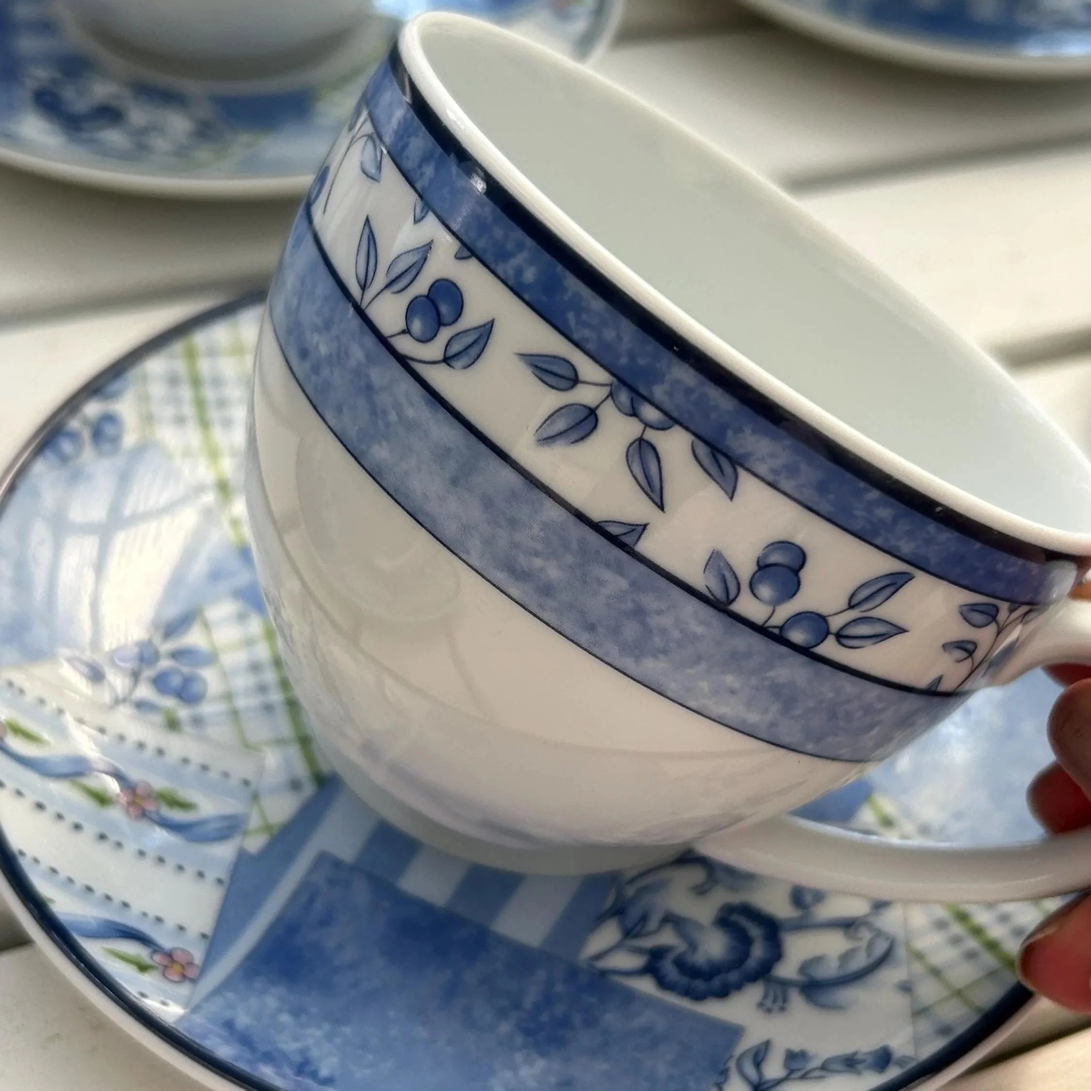 Angled close-up of the teacup rim and saucer showing the fine porcelain and floral band