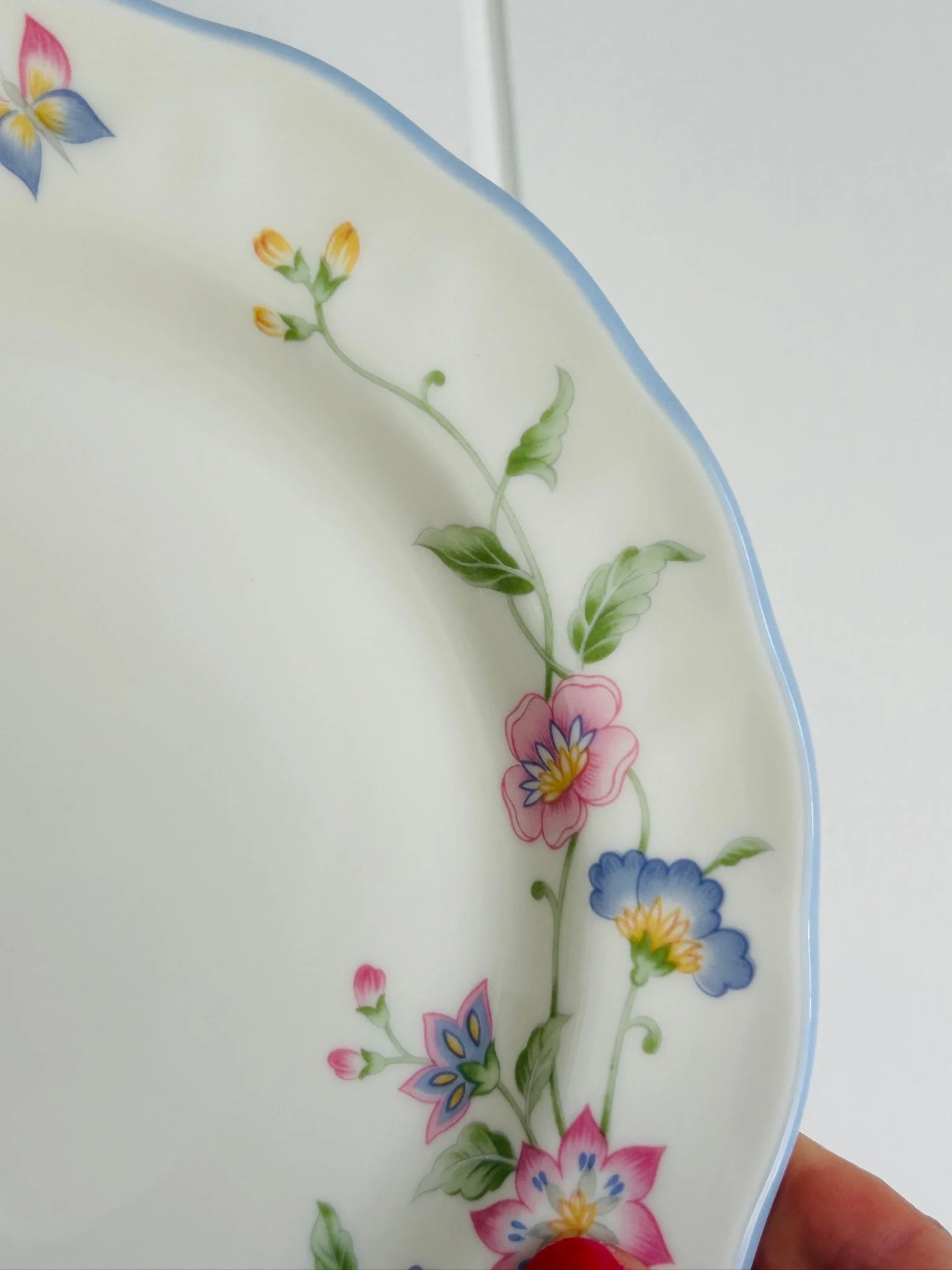 Close-up detail of the floral border with pink, yellow, and blue flowers on the softly scalloped rim.