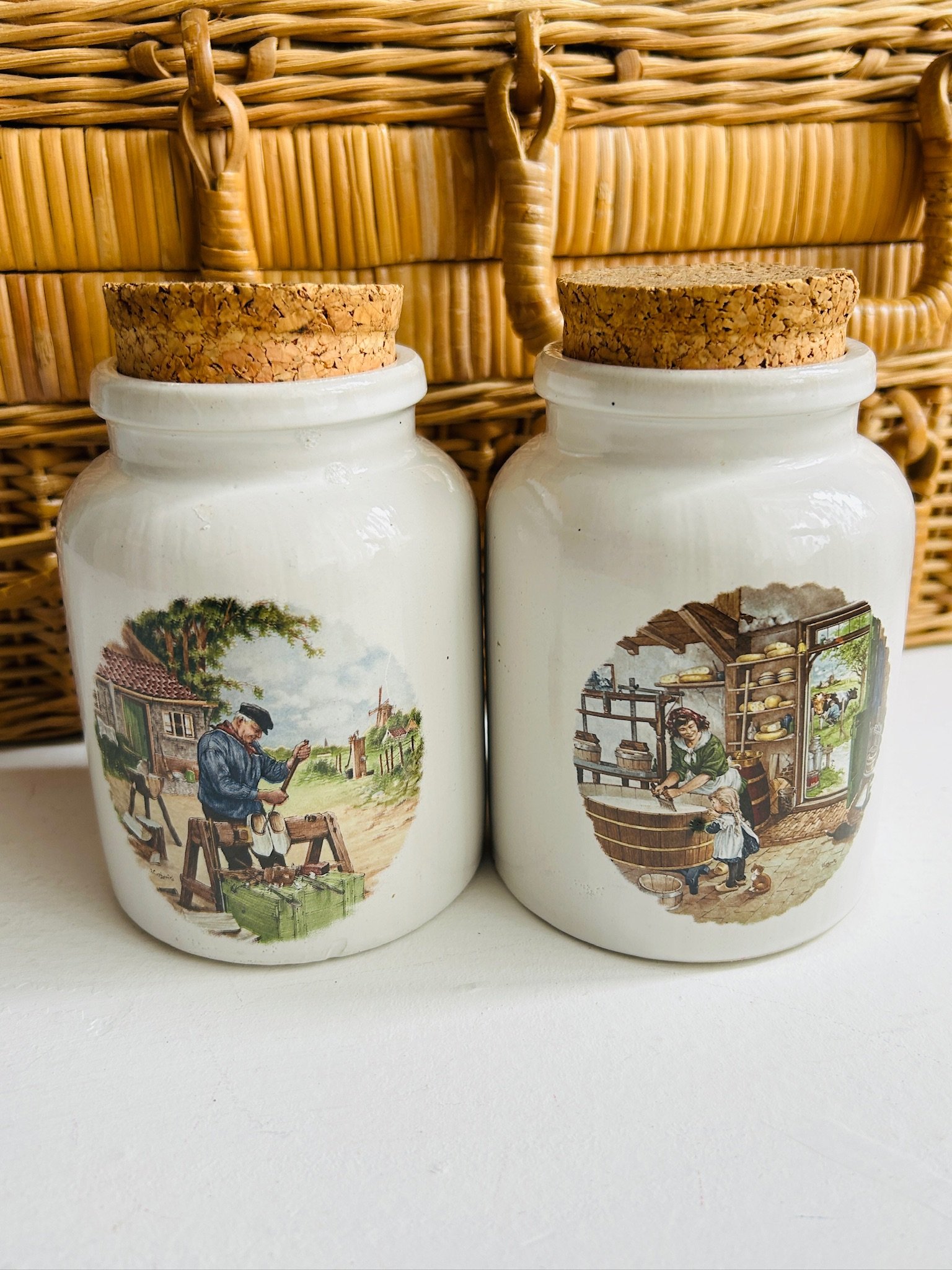 Both ceramic mustard pots displayed together, showing the matching shape, cork stoppers, and contrasting hand-painted scenes.