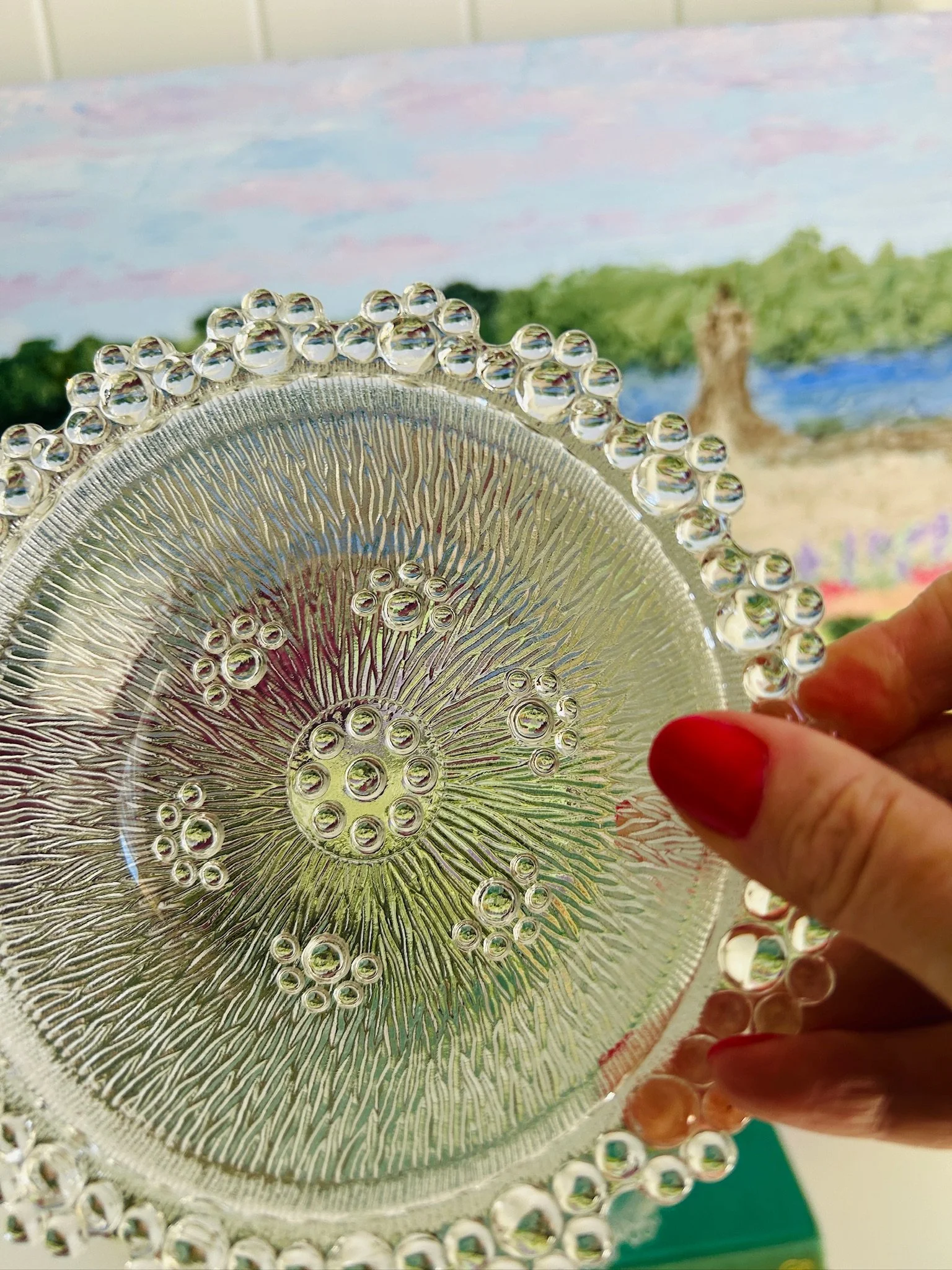 Angled top view of the bowl in hand, highlighting the clear pressed glass pattern and circular beaded edge.