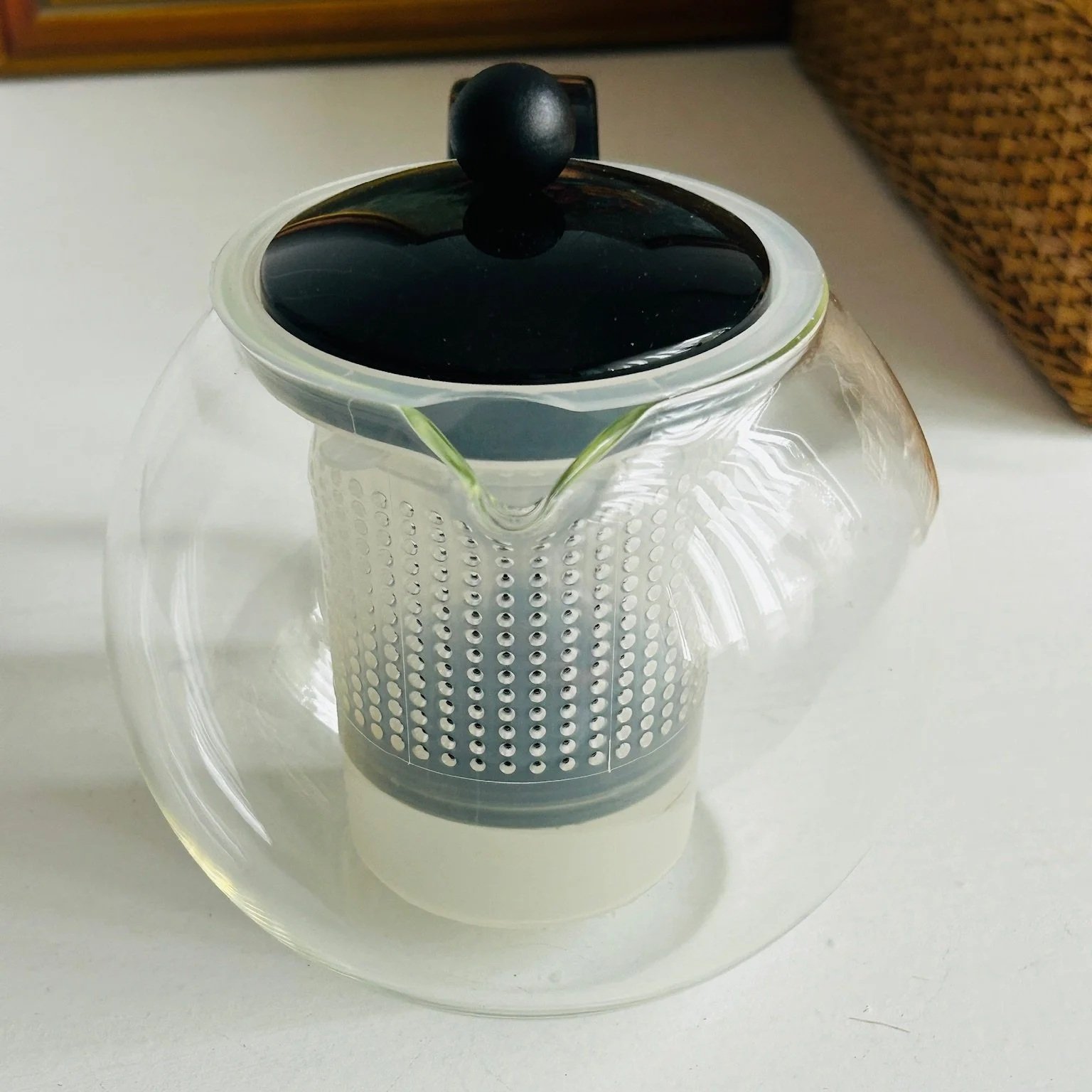 Side view of the Bodum Assam tea press styled on a table, showing the full teapot shape, black handle, and central infuser.