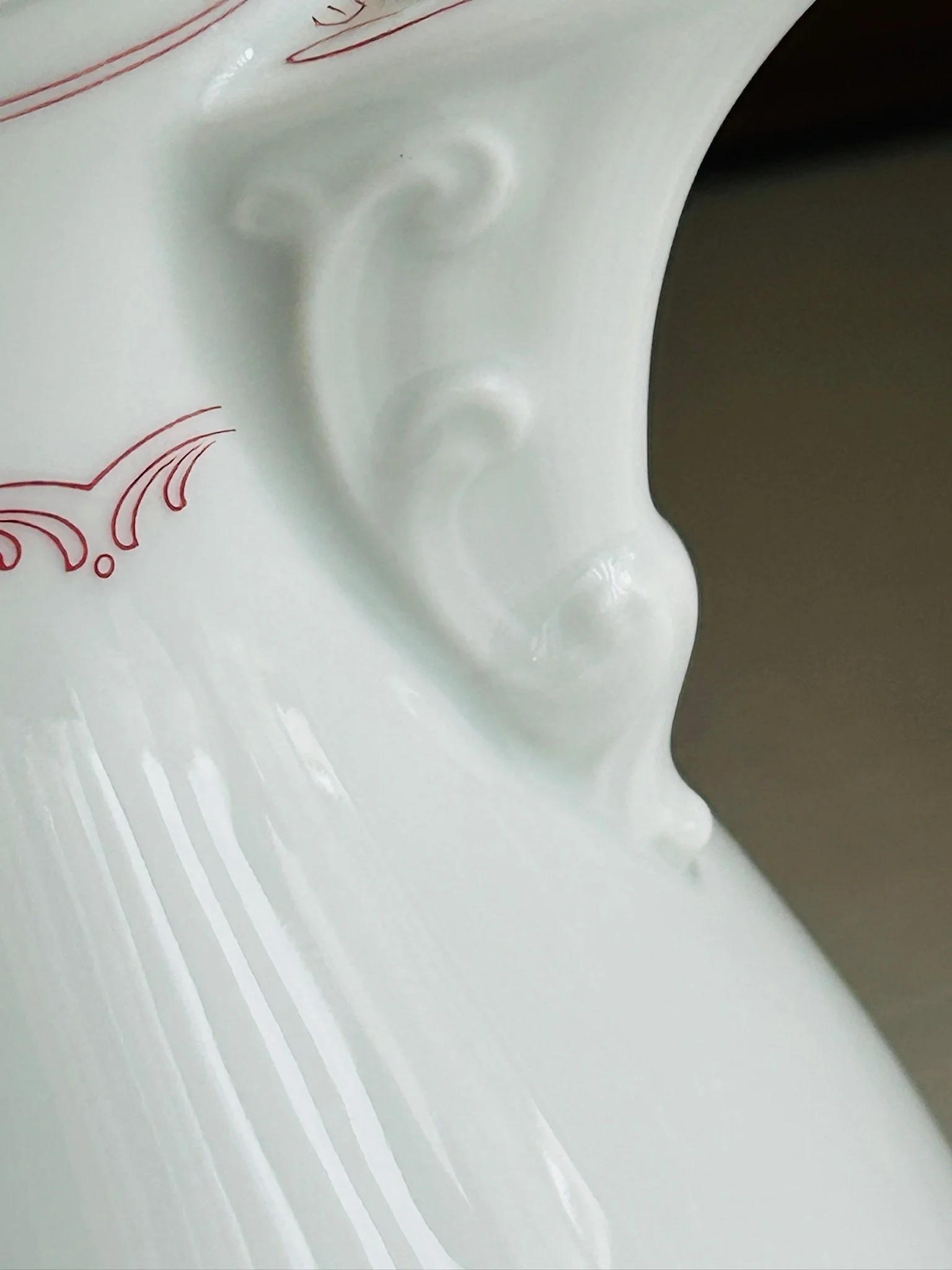 Close-up of the lower handle attachment and body detail, highlighting the moulded scroll shape and glossy glaze.