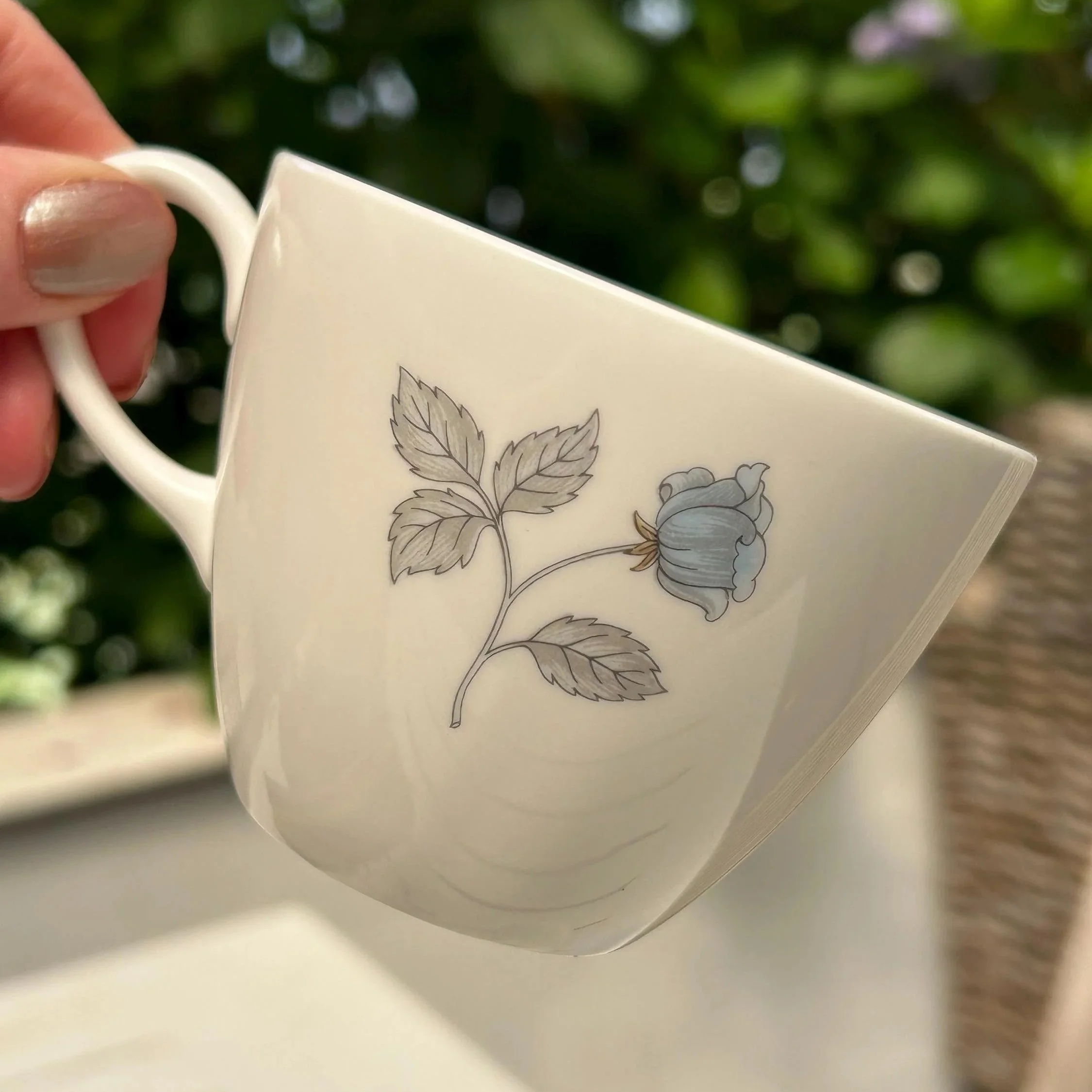 Reverse side of the teacup showing the secondary blue rose motif and elegant cup shape