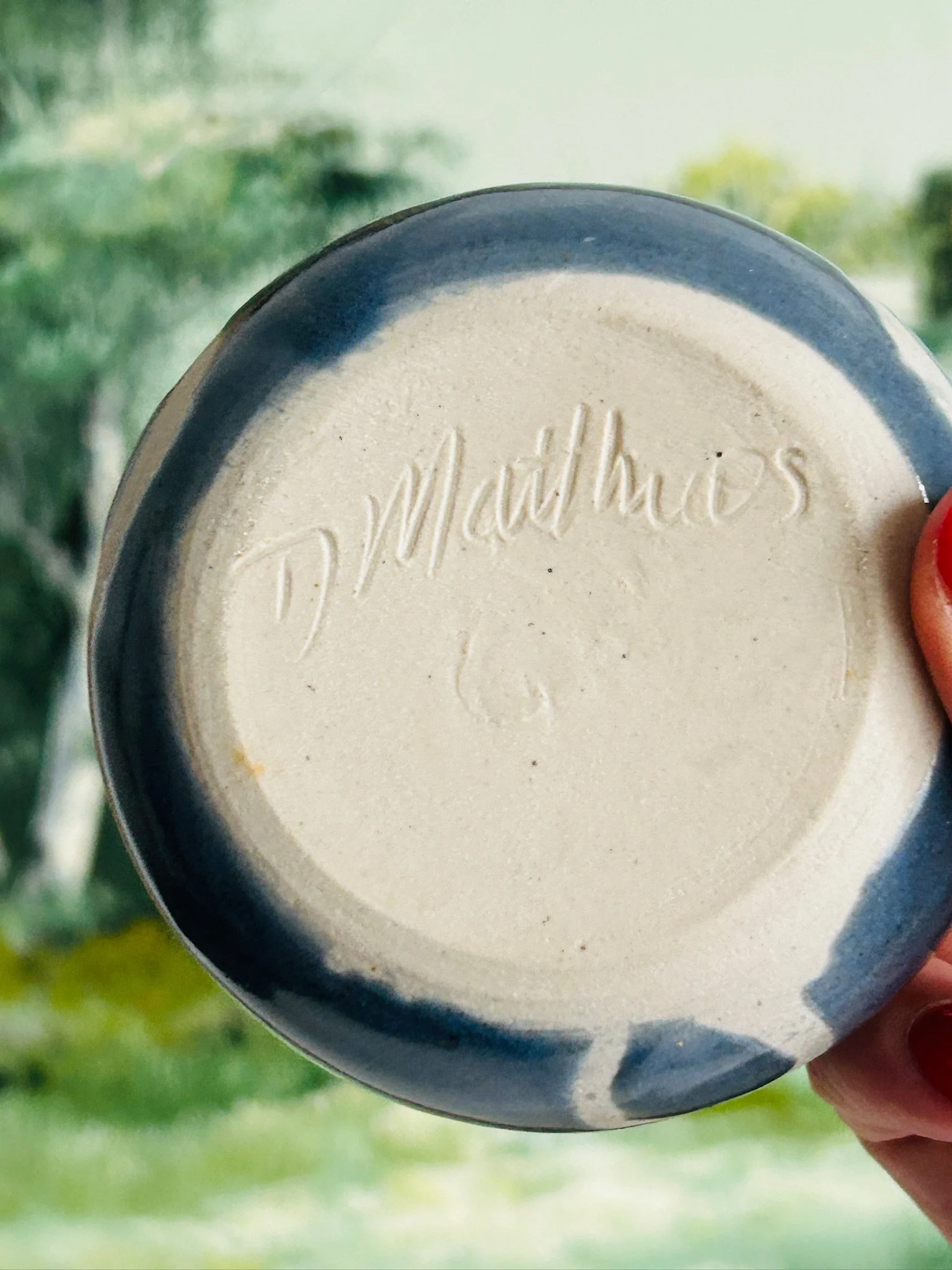 Underside of the pottery bowl showing the impressed D Matthews signature on the unglazed base