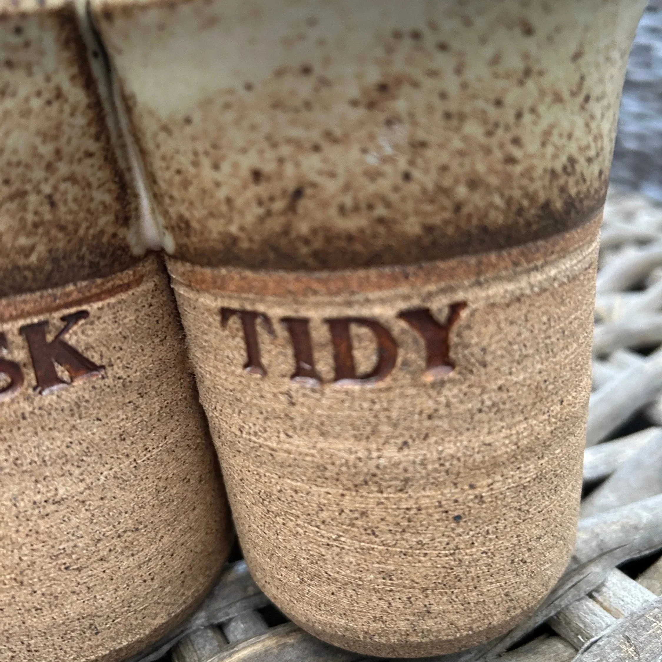 Close-up of impressed words “DESK” and “TIDY” in brown clay