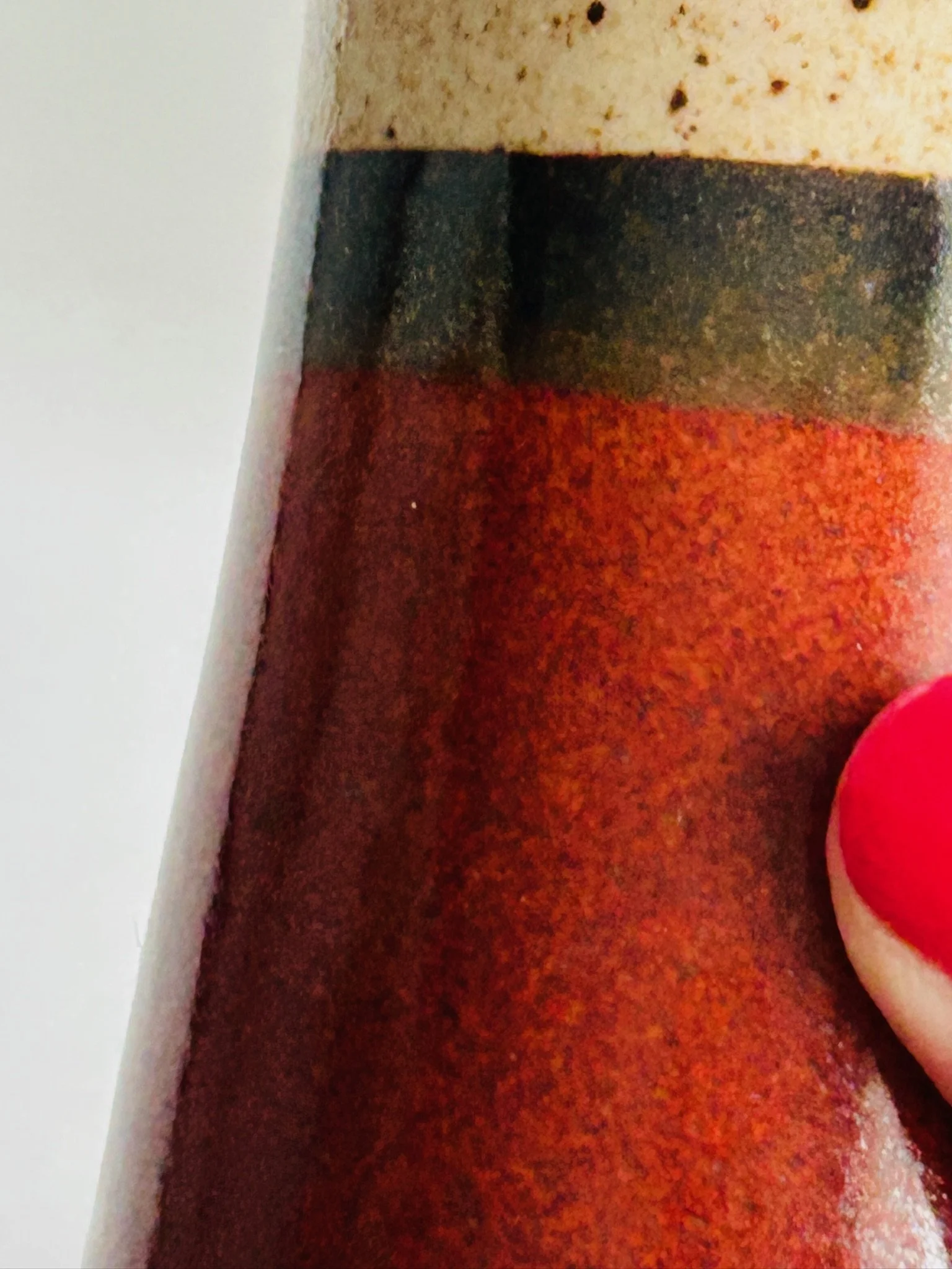 Two vintage ceramic shakers displayed on a woven rattan surface, one upright and one resting on its side.