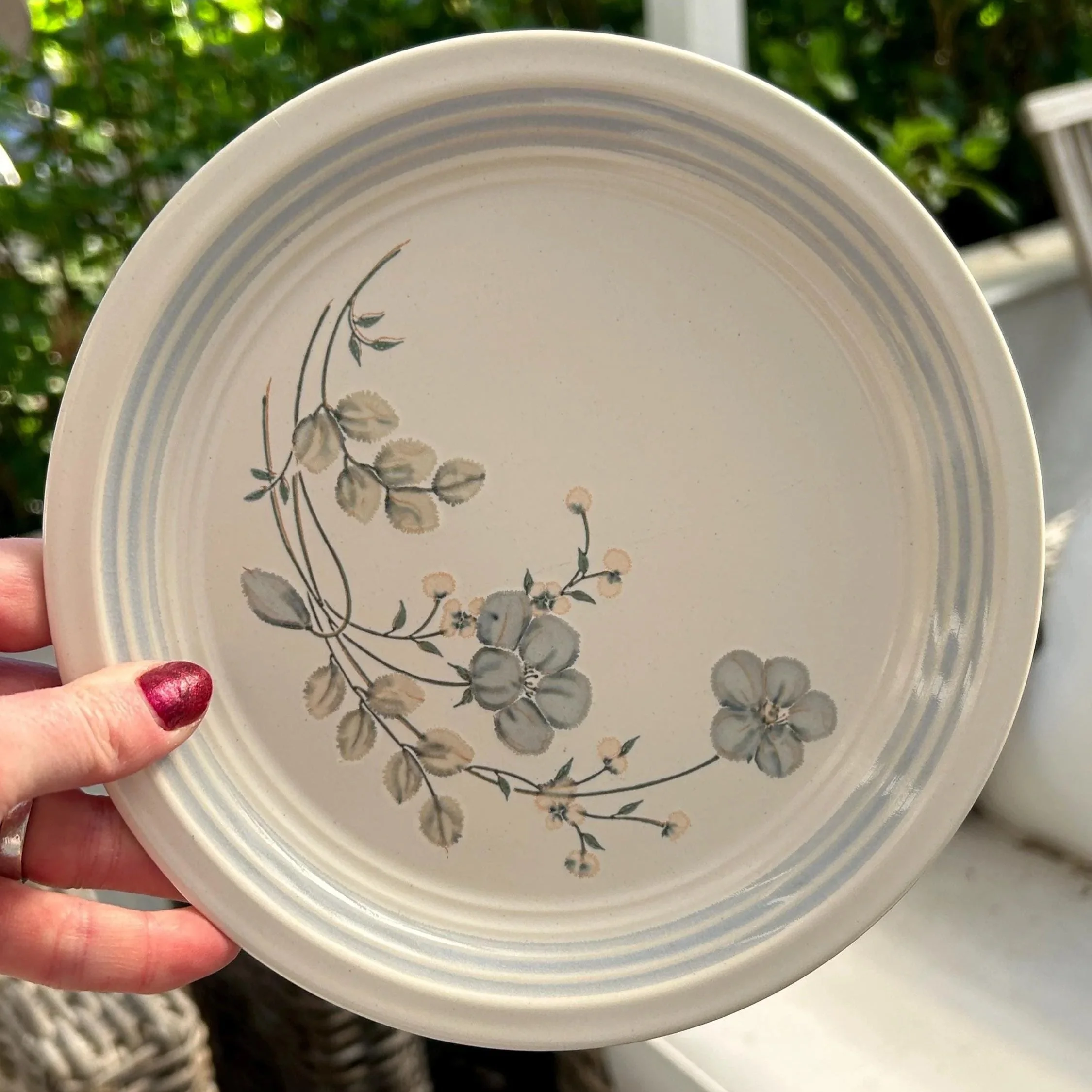 Hand holding side plate showing floral placement and rim detailing