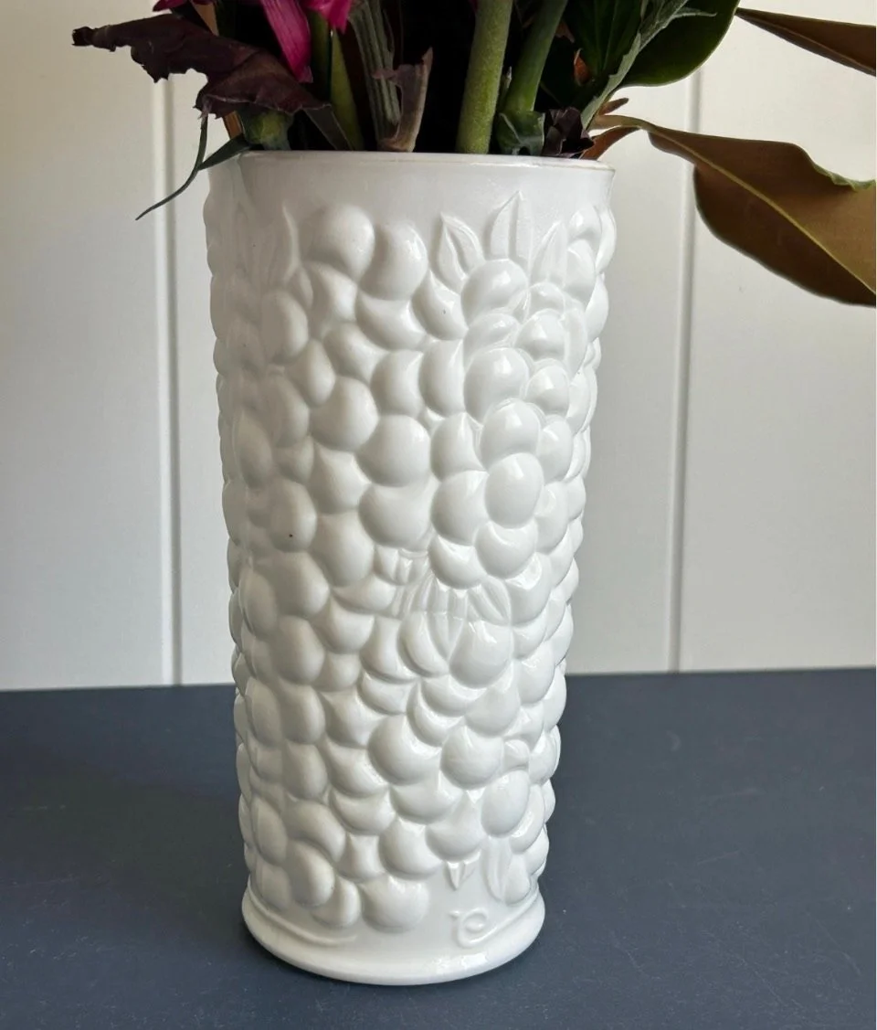 White grapevine relief vase photographed from above against a navy surface