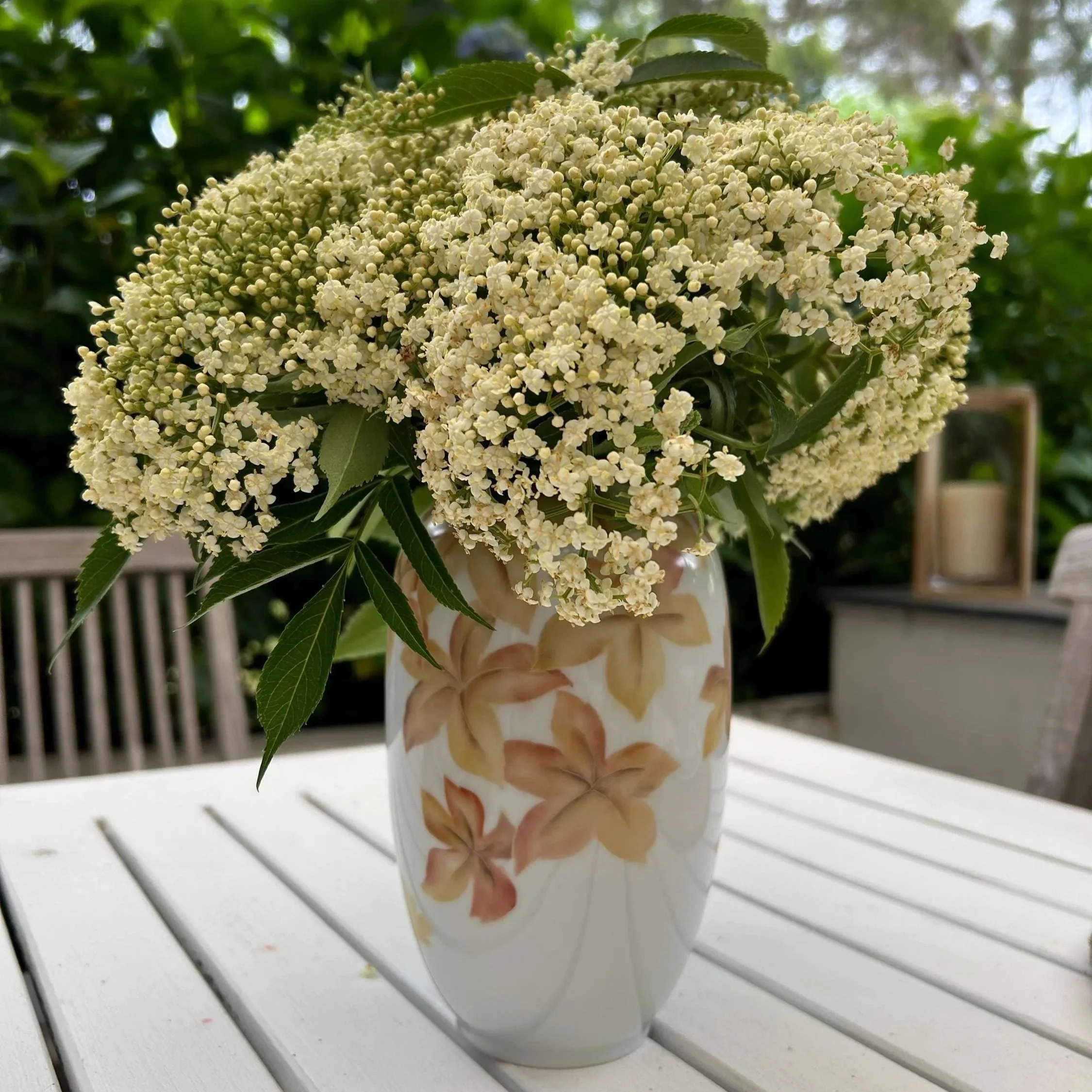 Vase on outdoor table with white flowers arranged inside