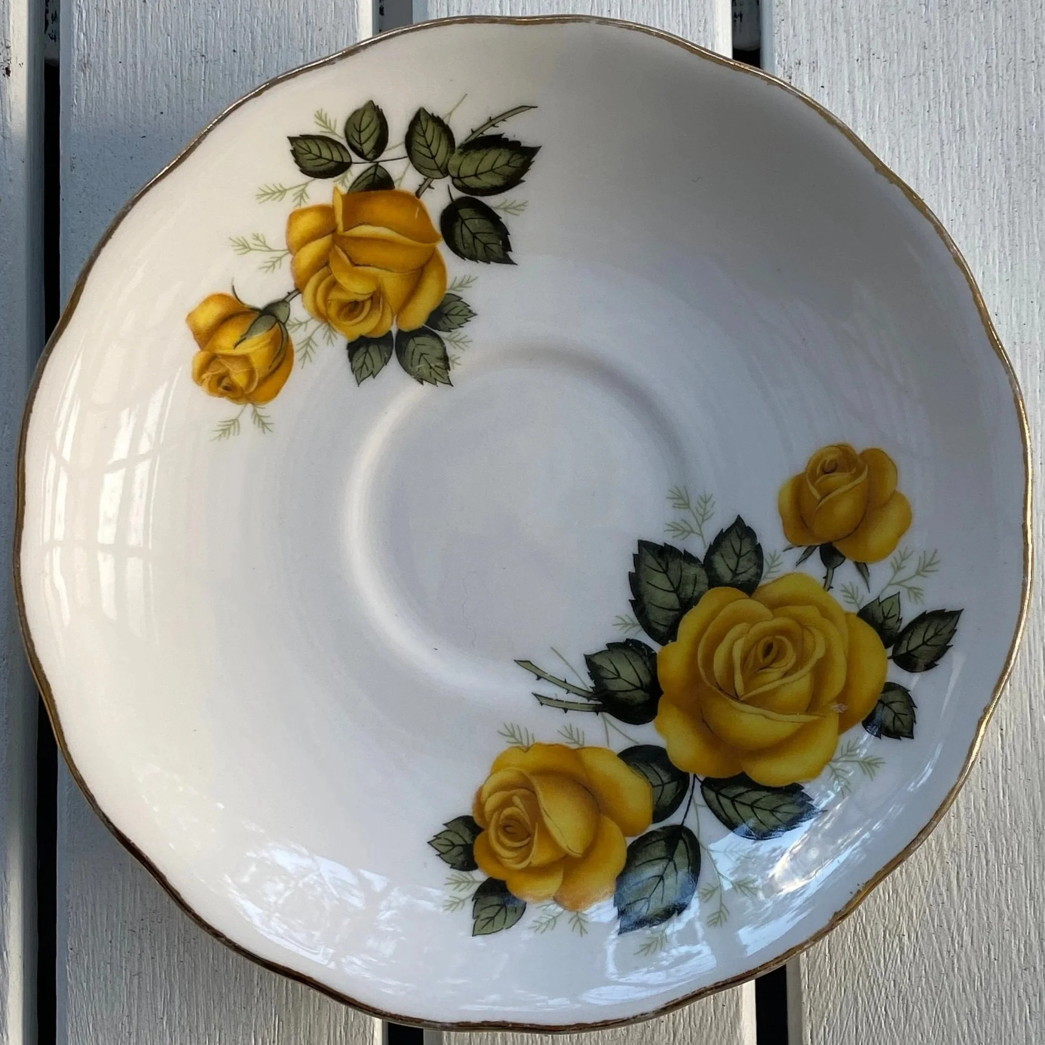 Front view of Royal Vale saucer showing yellow roses and scalloped gold-trimmed edge
