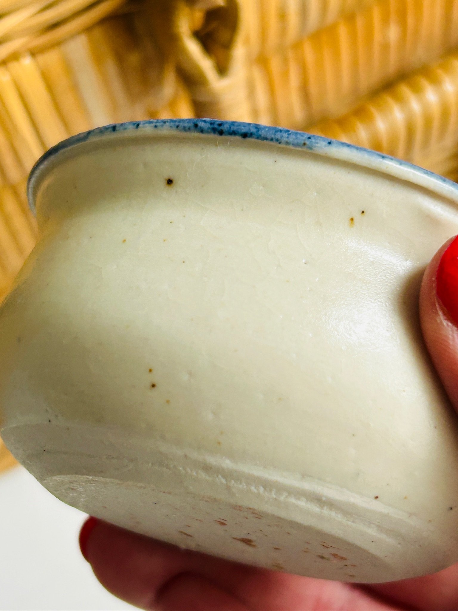 Close side detail of the bowl showing the curved handmade body, blue-edged rim, and subtle glaze variation