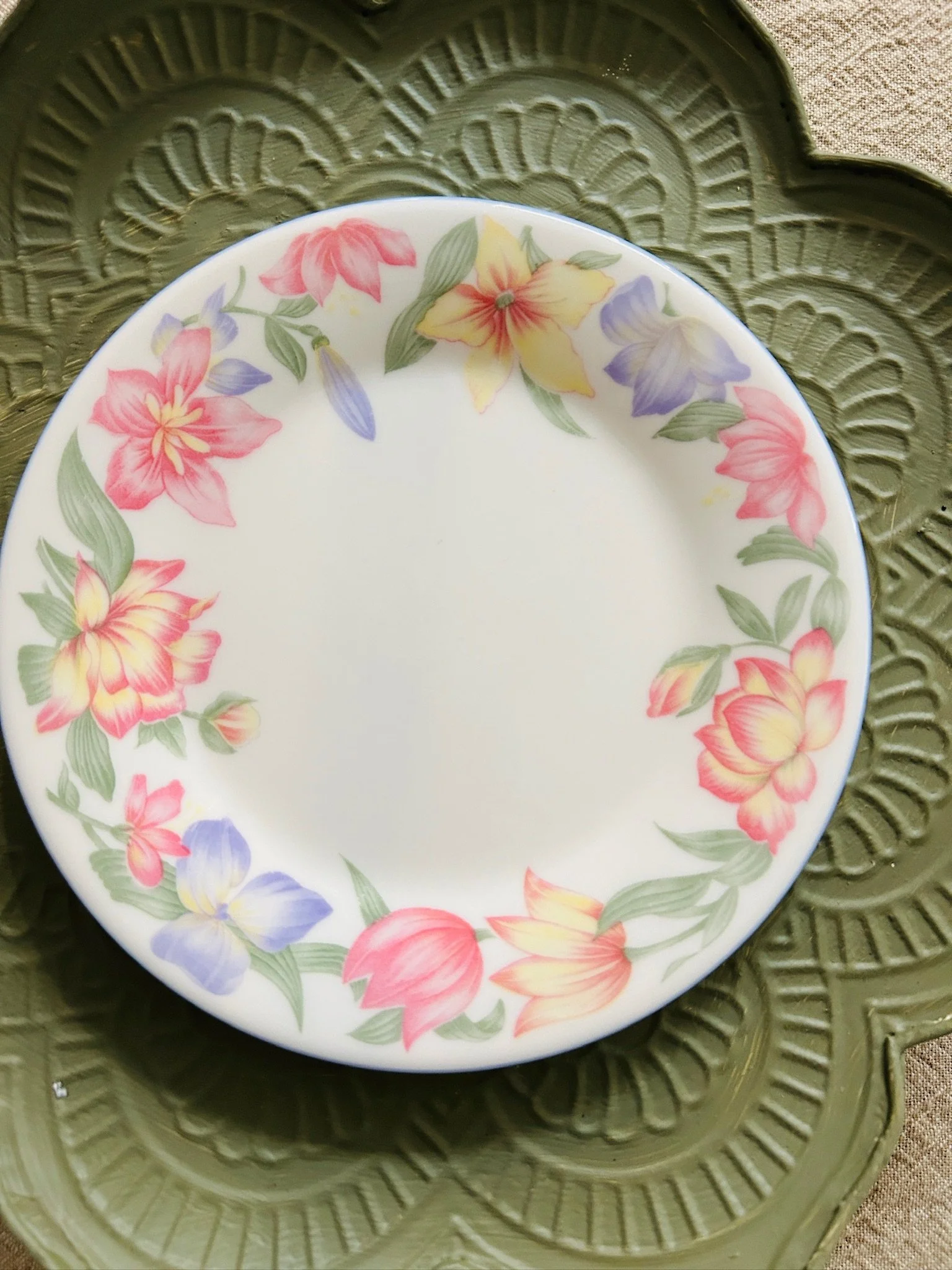 Single side plate displayed flat, highlighting the delicate floral garland and clean white centre