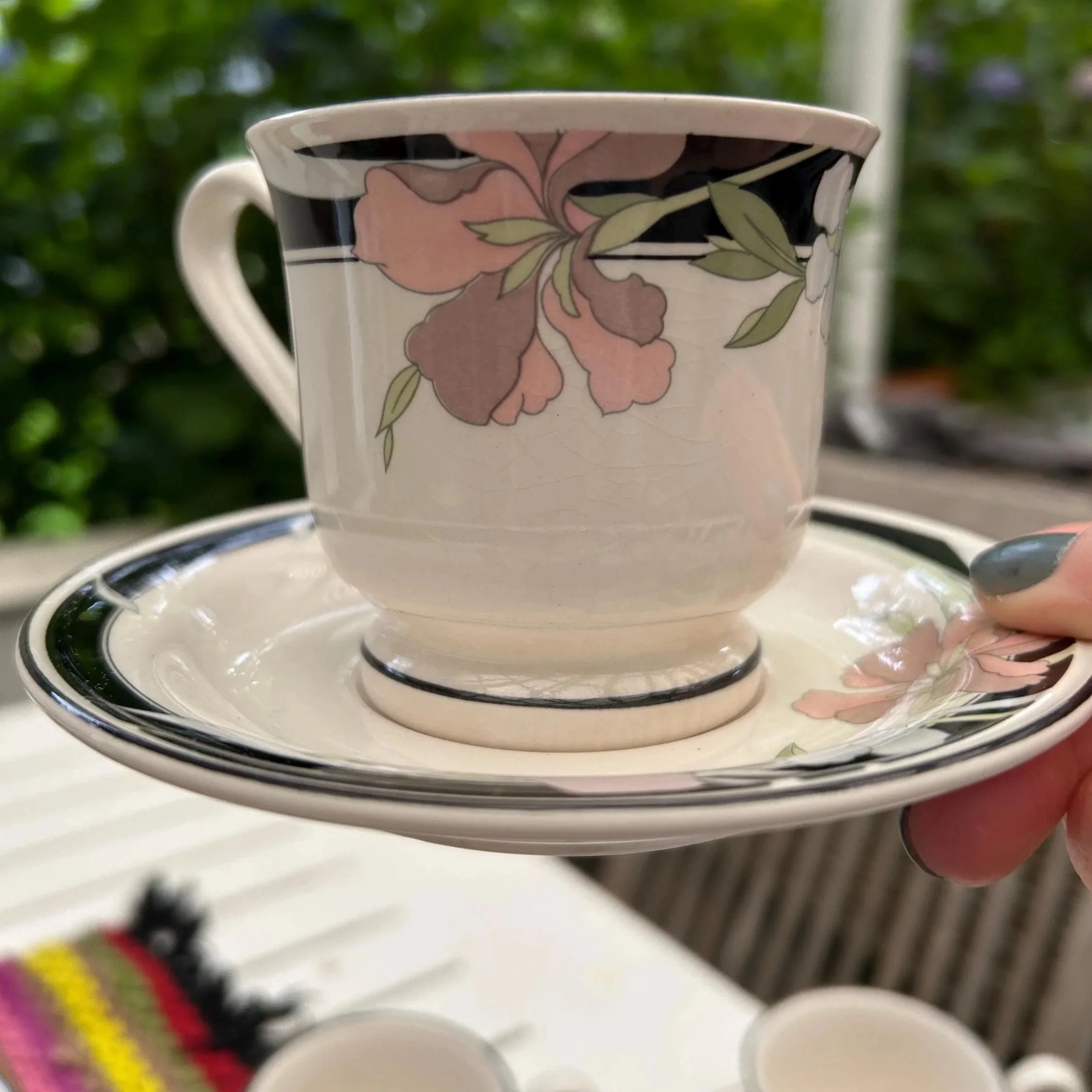 Close-up of one cup and saucer showing pastel florals and bold black trim