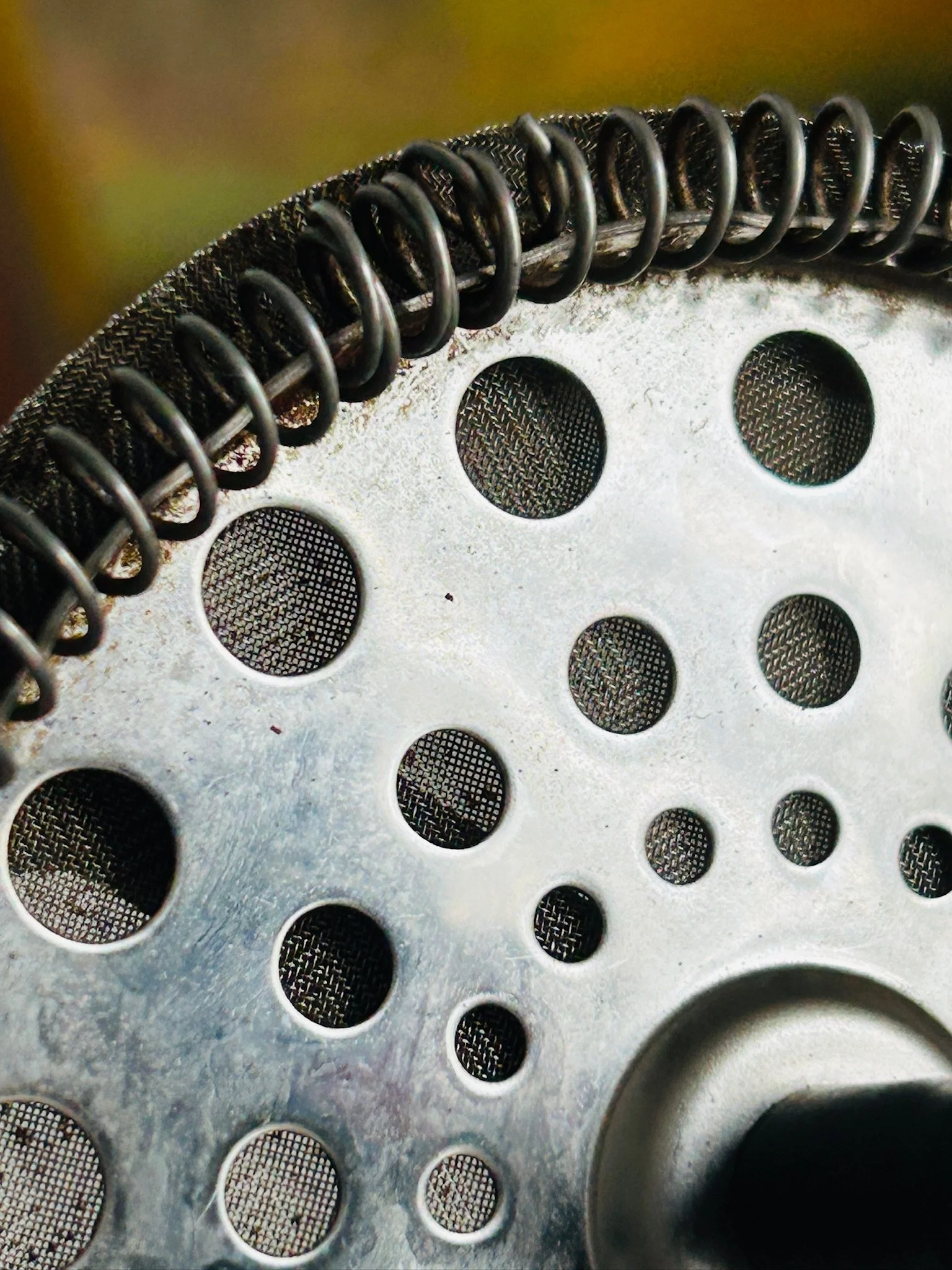Close-up of the mesh filter edge and perforated metal plate, showing the circular spring detail.