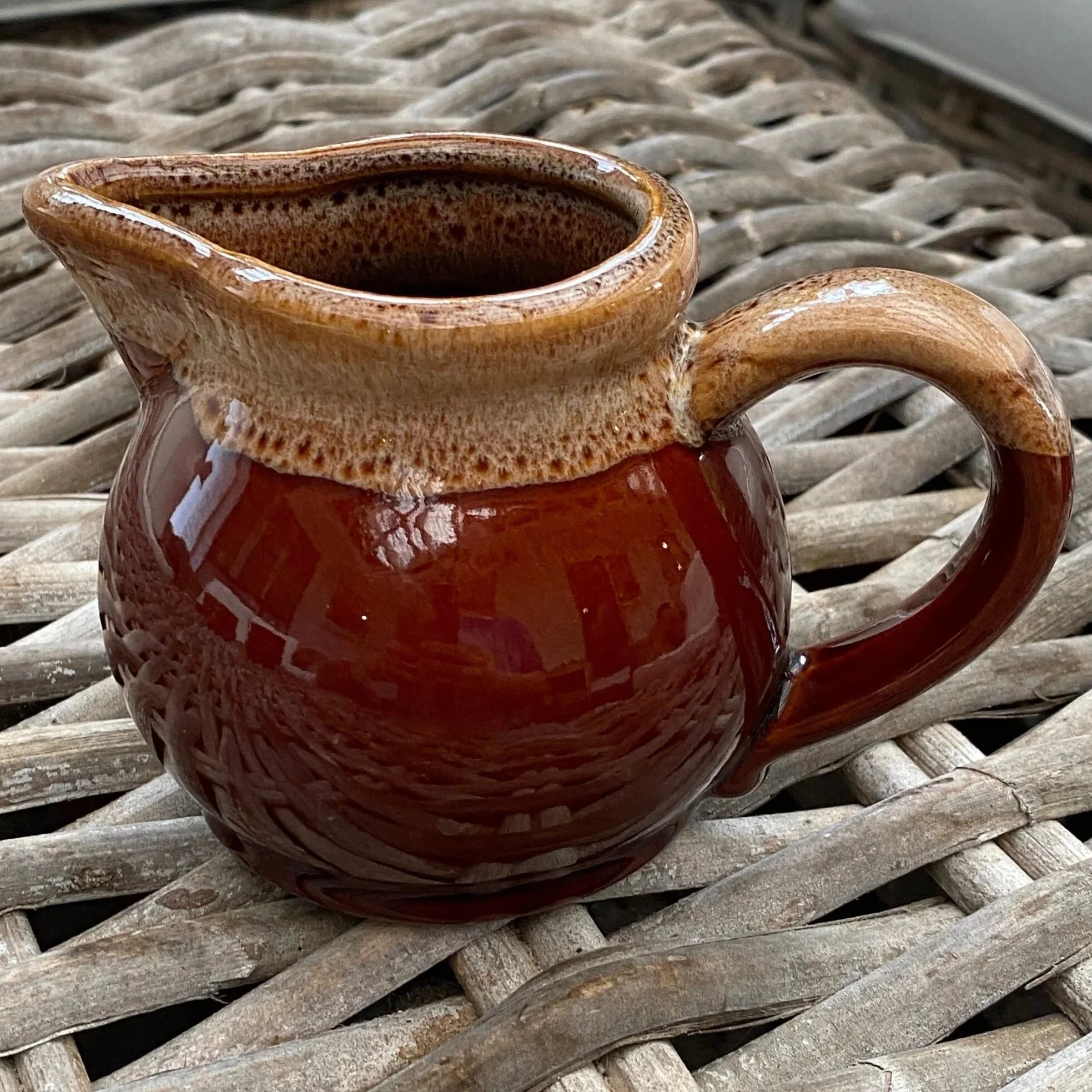 Side profile of vintage brown creamer with tan drip-glaze rim