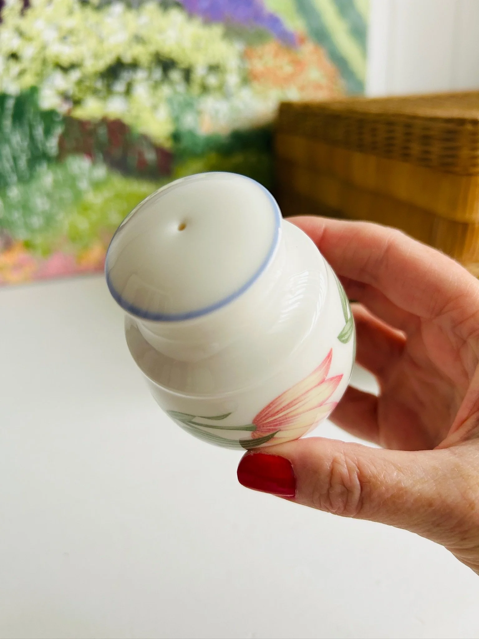 Top view of the matching shaker held in hand showing the single shaker hole and blue rim detail