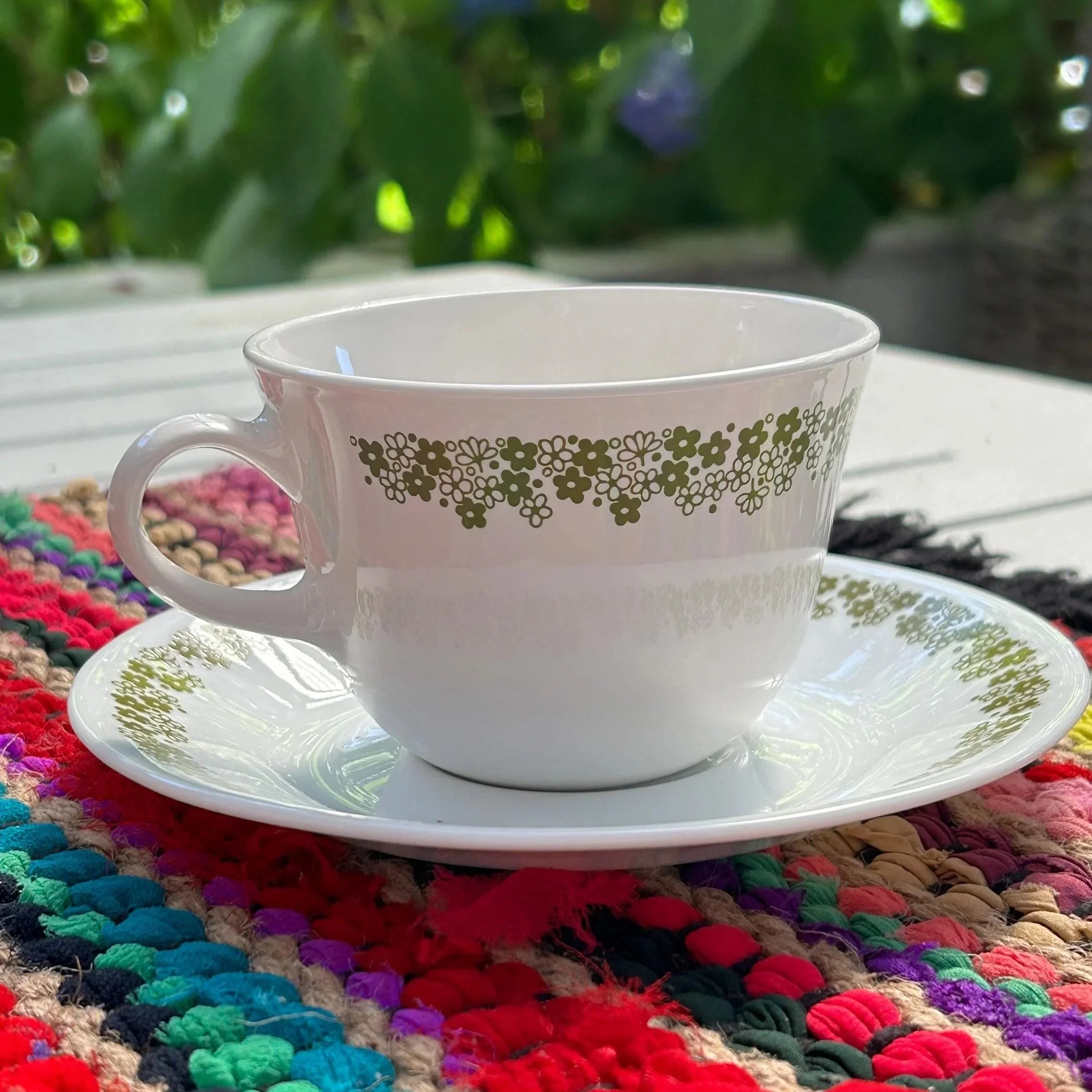 Vintage Corelle Spring Blossom teacup and saucer in green floral Crazy Daisy pattern. Durable Vitrelle glass. Made in USA, 1970s.