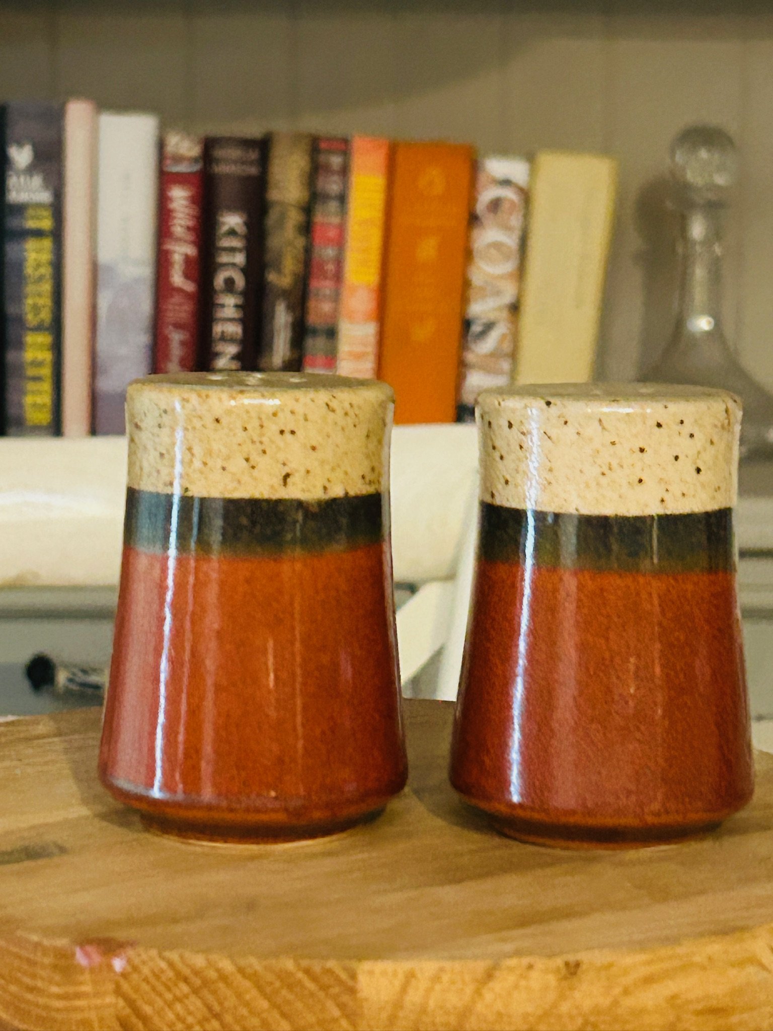 Pair of vintage Japanese ceramic salt and pepper shakers with cream speckled tops and reddish-brown bodies displayed side by side on a wooden surface.