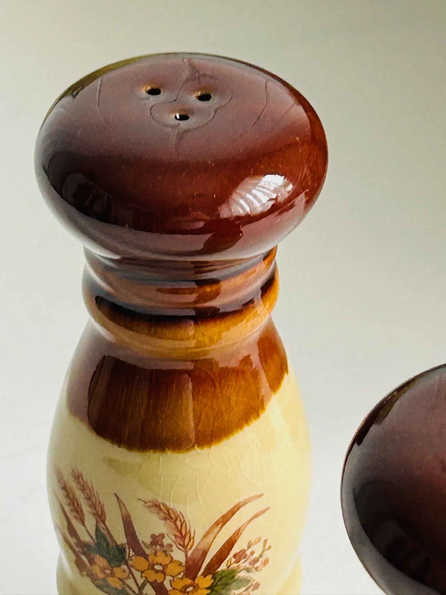 Detailed close-up of the floral and wheat transfer pattern on one shaker