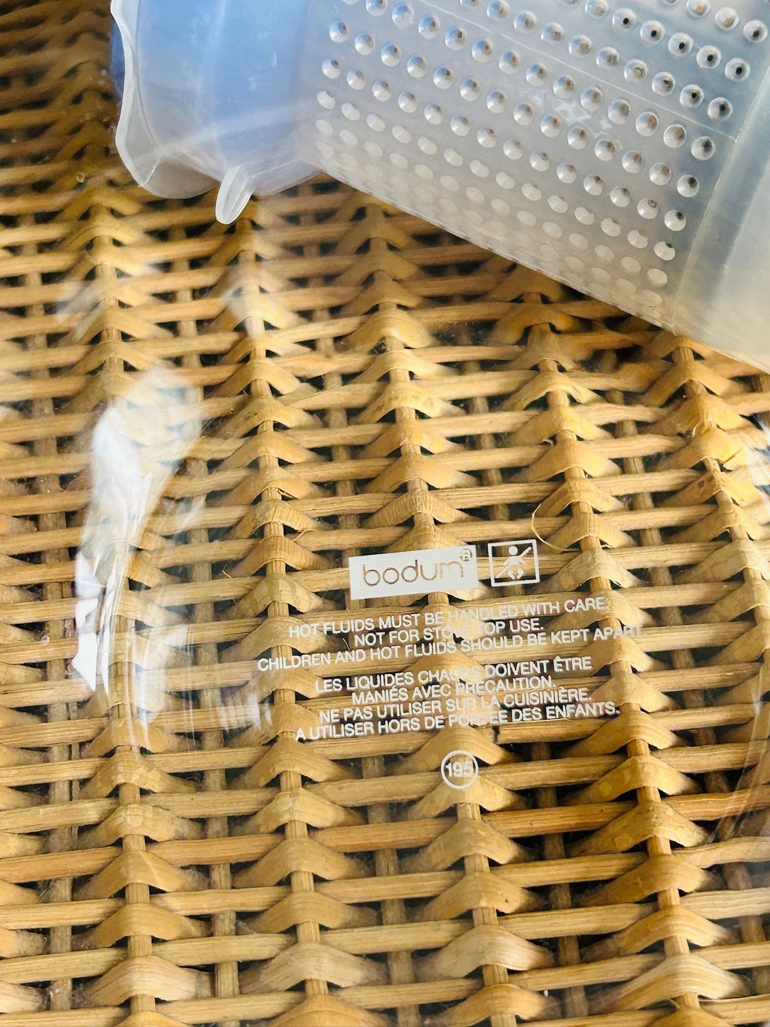 Close-up of the printed Bodum logo and safety markings on the clear glass teapot body.