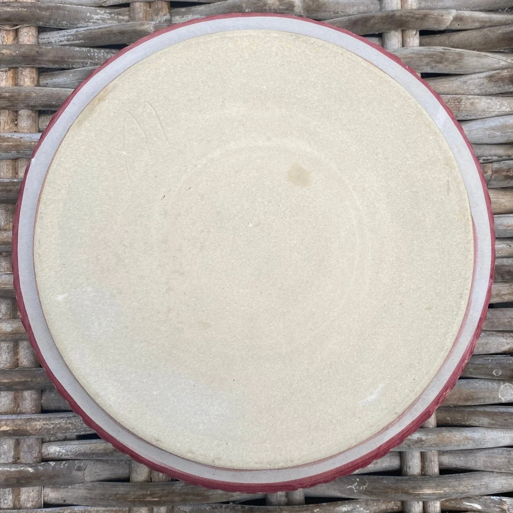 Base of the pottery dish showing the unglazed bottom and subtle maker’s mark