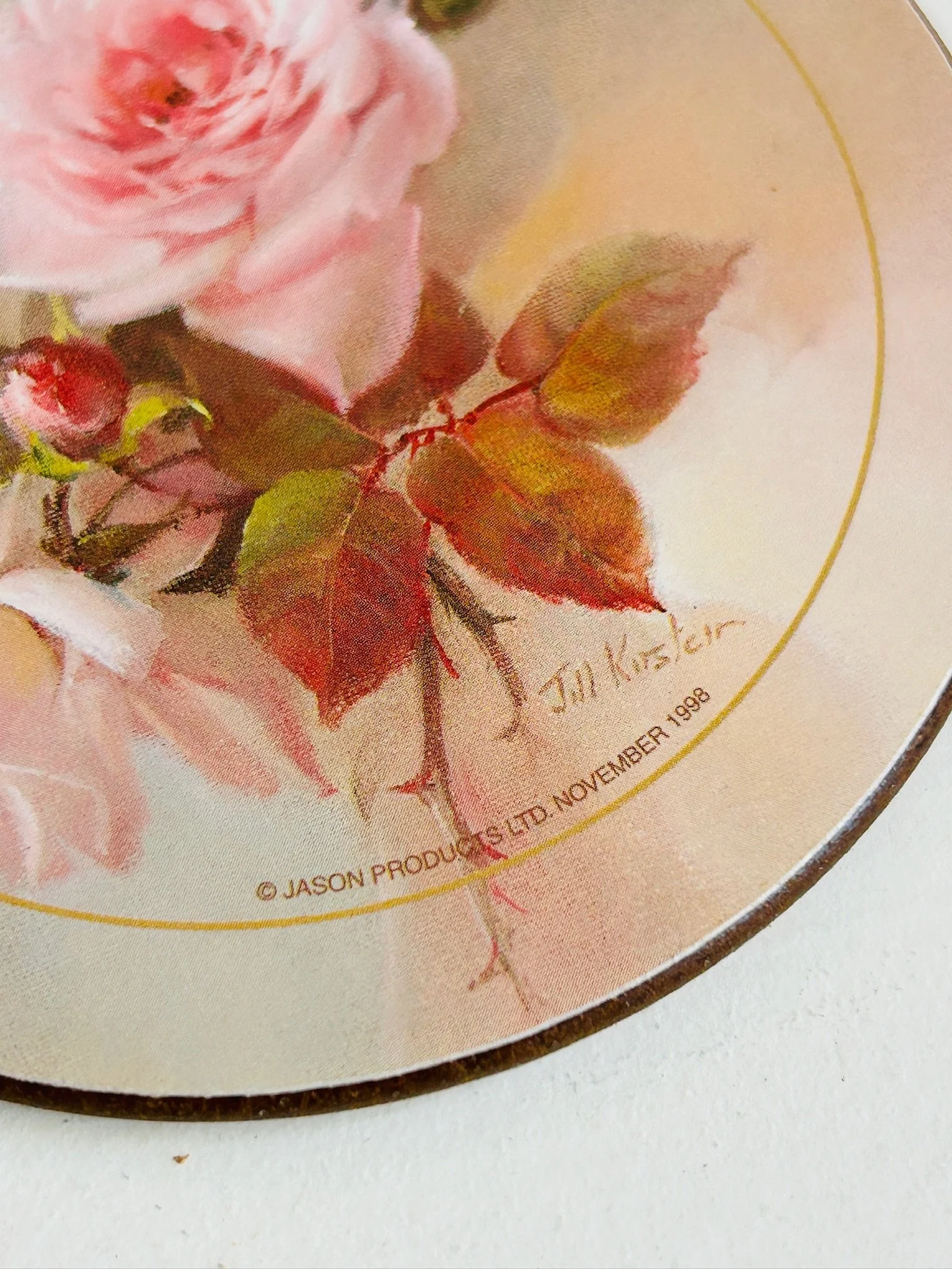 Close detail of Jill Kirstein signature and Jason Products Ltd November 1998 copyright mark on a rose placemat